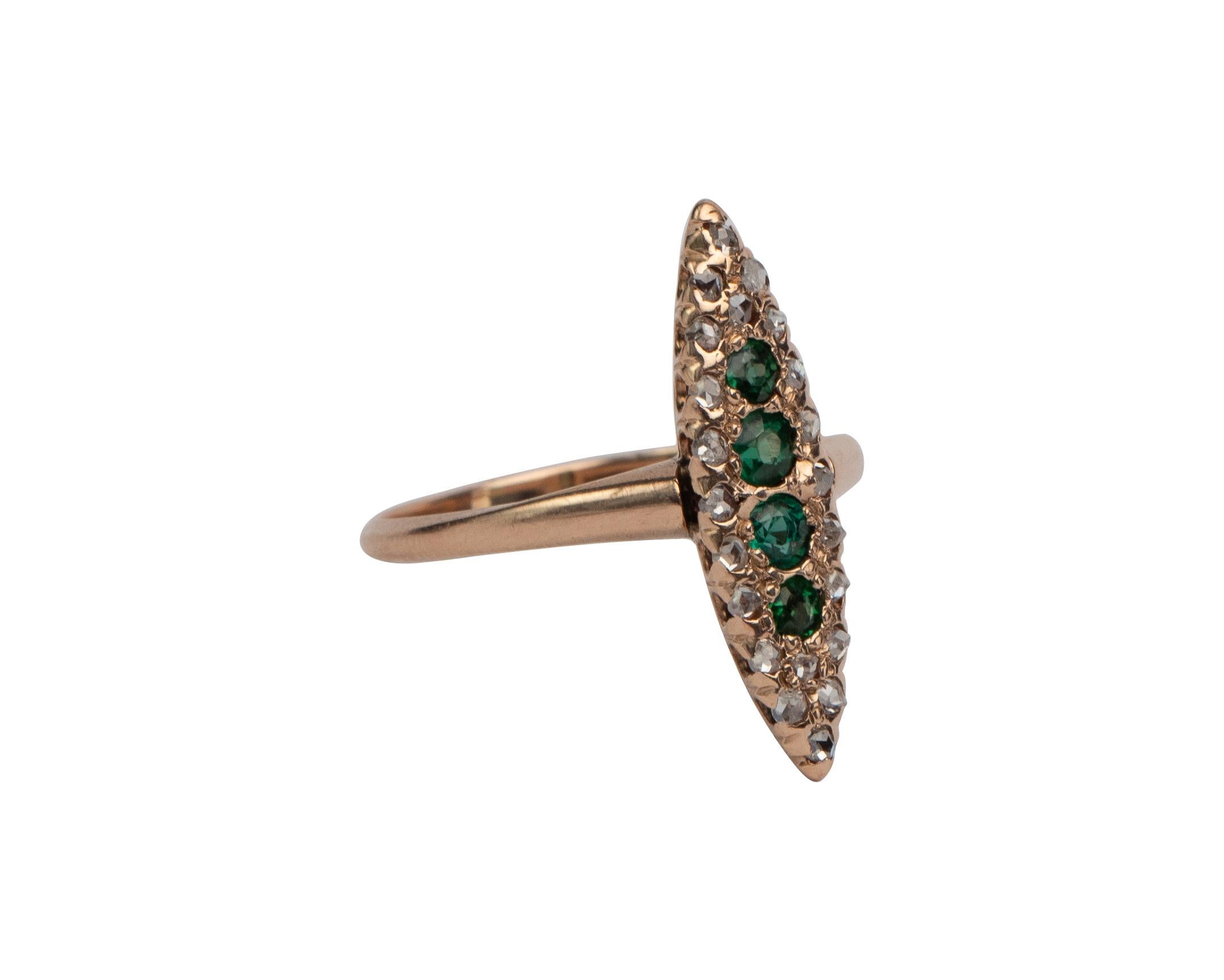 This is a fantastic example of a victorian era navette marquise-shaped ring. It is crafted in a beautiful rosey toned yellow gold and the center features four intense green emeralds of the finest quality. The rubies are surrounded by a border of