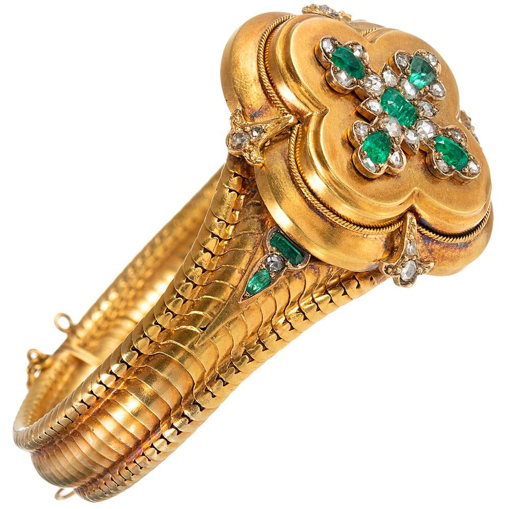 An exceptional example of antique finery, the bracelet is made of 18 karat yellow gold and decorated with a cross-shaped cluster of intense green emeralds and rose cut diamonds. The emeralds exhibit magnificent color that is striking and beautiful.