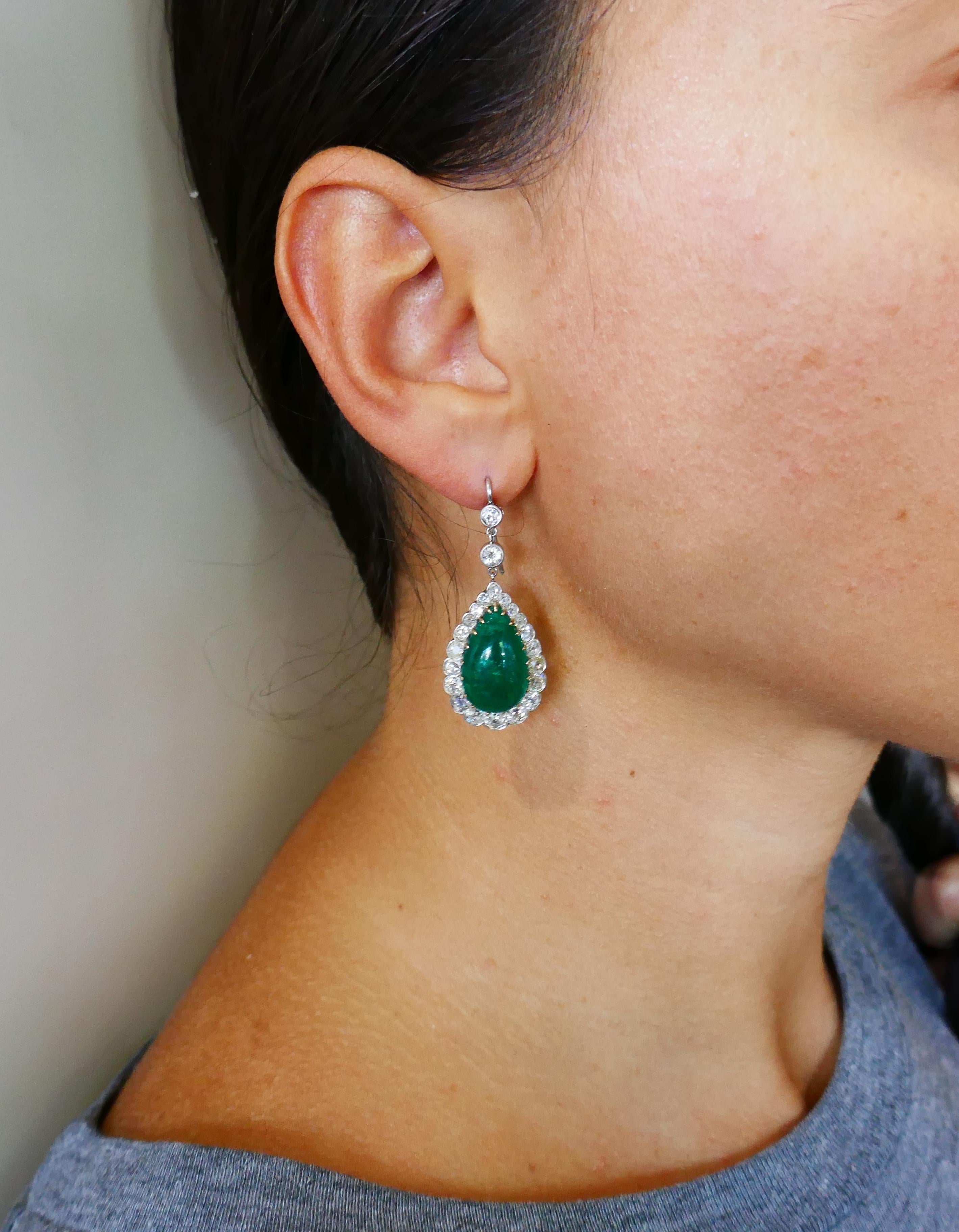 Classic emerald and diamond dangle earrings that are a great addition to your jewelry collection.
The earrings are made of 14 karat (tested) yellow gold and silver and feature cabochon emeralds framed with a row of old-mine and Old European cut