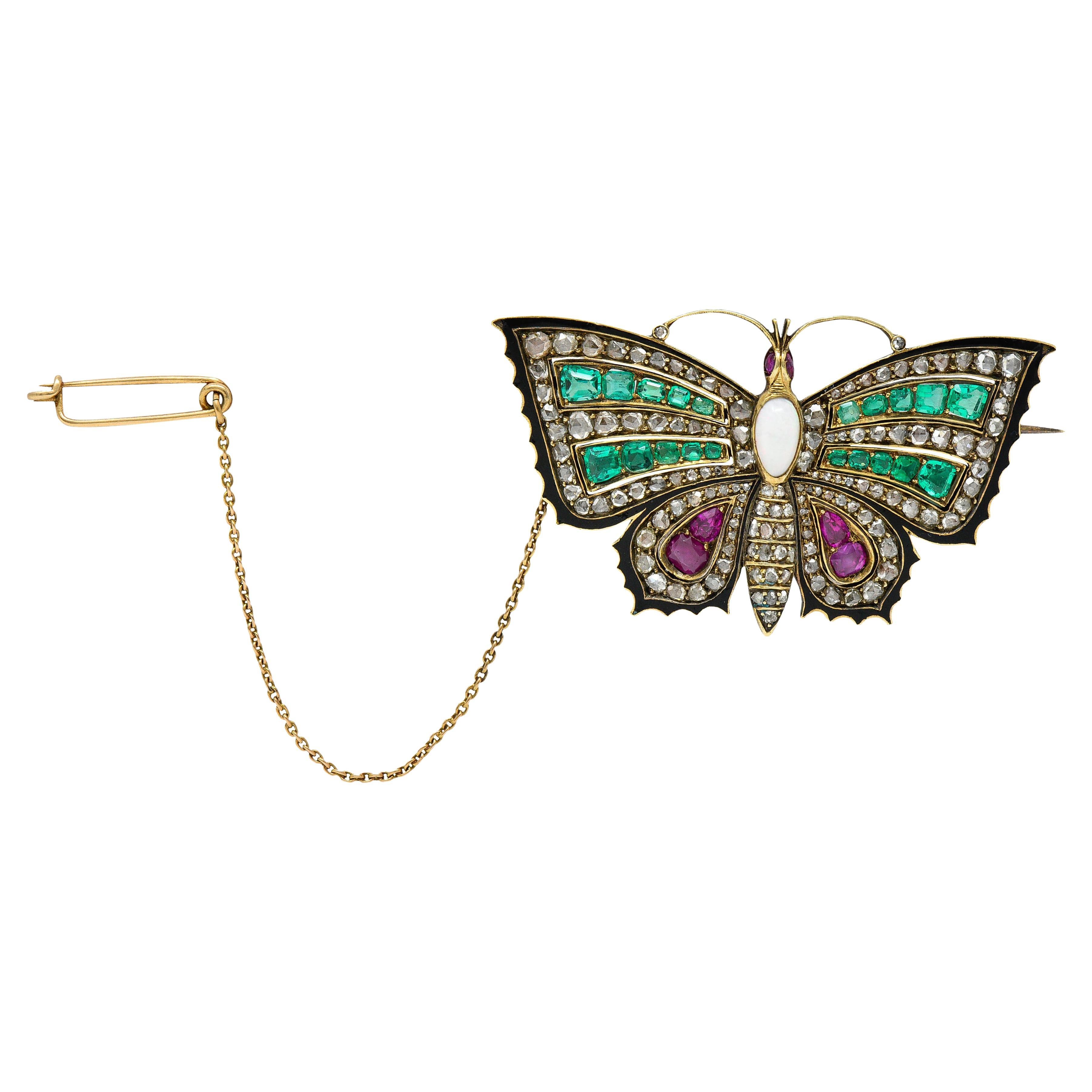 Butterfly brooch is designed with spread gem set wings glossed with a black enamel border - some loss

Four rows of bright bluish green emeralds graduating in size while weighing in total approximately 1.95 carats

With cushion, pear, and cabochon