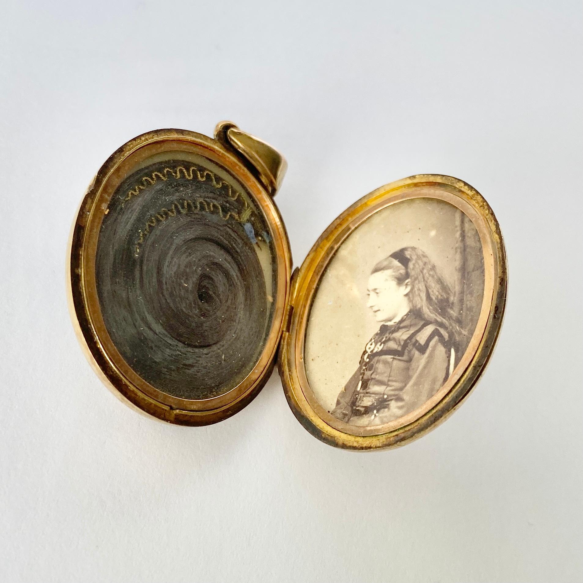 The enamel on this locket is black and wonderfully glossy, it really makes the gold pop. The locket also holds a cross on the front with the words 'in memoriam'. The back of the locket is simple gold and the inside holds a lock of hair and a picture