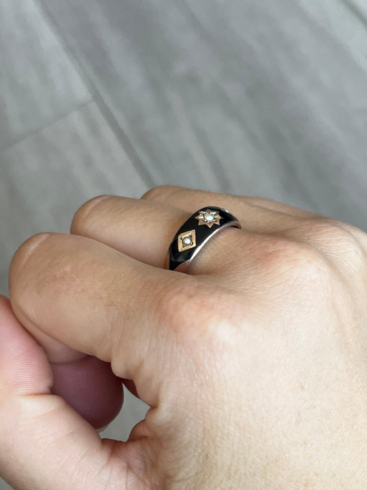 This black enamel band is modelled in 9carat gold and holds three seed pearls in starburst settings. Hallmarked Chester. 

Ring Size: Q or 8 1/4
Band Width: 6.5mm

Weight: 3.9g


