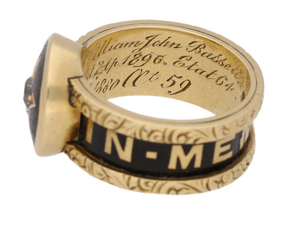 Victorian diamond set family memorial ring. The raised circular bezel set centrally with a cushion shape old cut diamond in an open back grain setting with an approximate weight of 0.30 carats, within a star shape motif with black enamel surround,