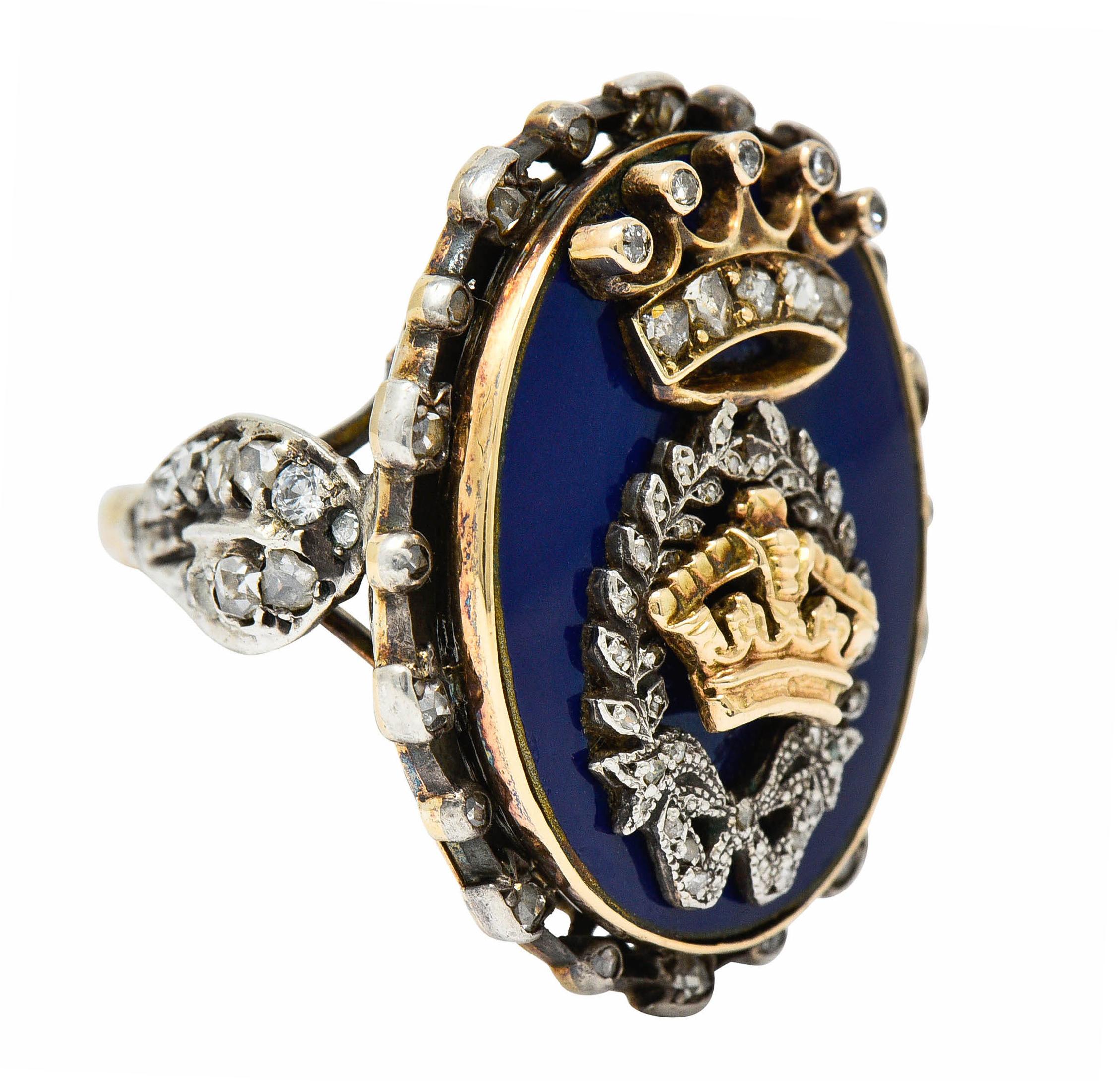 Oval statement ring depicts two gold crowns with a silver laurel motif

Surrounded by ultramarine blue enamel - exhibiting no loss

With a rose cut diamond halo and cathedral shoulders

Tested as silver-topped 18 karat gold

Circa: 1870

Ring Size: