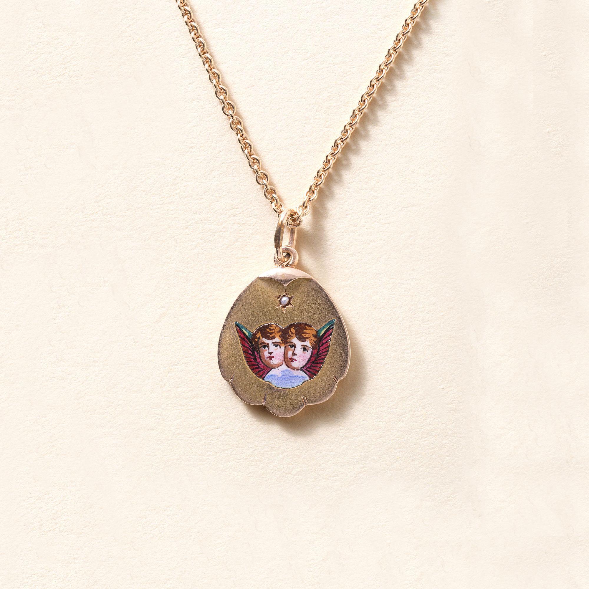 This Victorian pendant features dual faces of young angels
enameled on 14K Gold with an 18K rose gold chain.
Circa 1890s
Seashell shaped frame with a single seed pearl set at the top.
1 inch length with bale x 0.6 inch width
16 inch chain