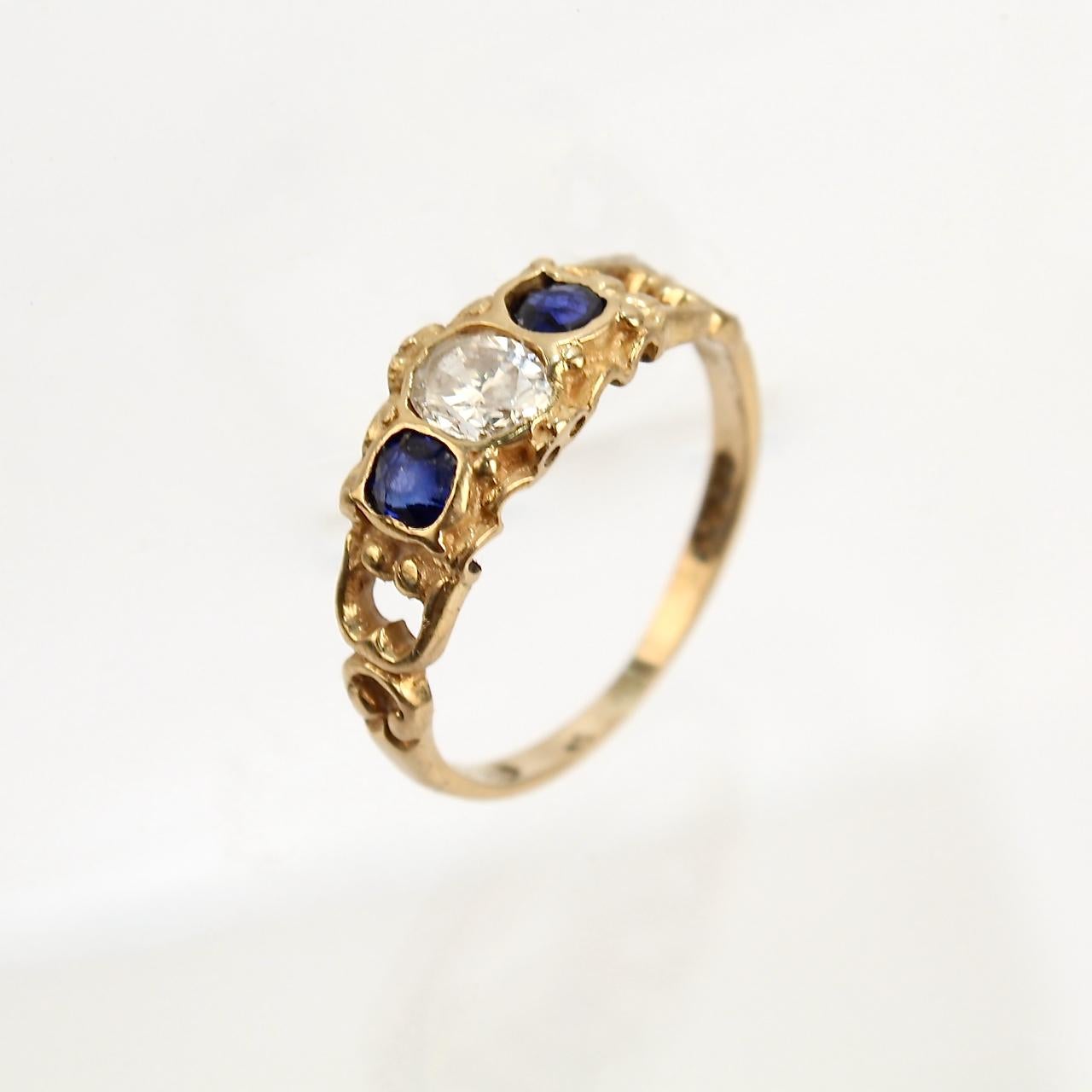 A very fine Victorian style English 18K gold, sapphire, & diamond ring. 

With a faceted oval diamond bezel set between two dark blue sapphires. The ring has a beautiful matte finish to the gold around the stones. 

A wonderful ring!

Date:
20th