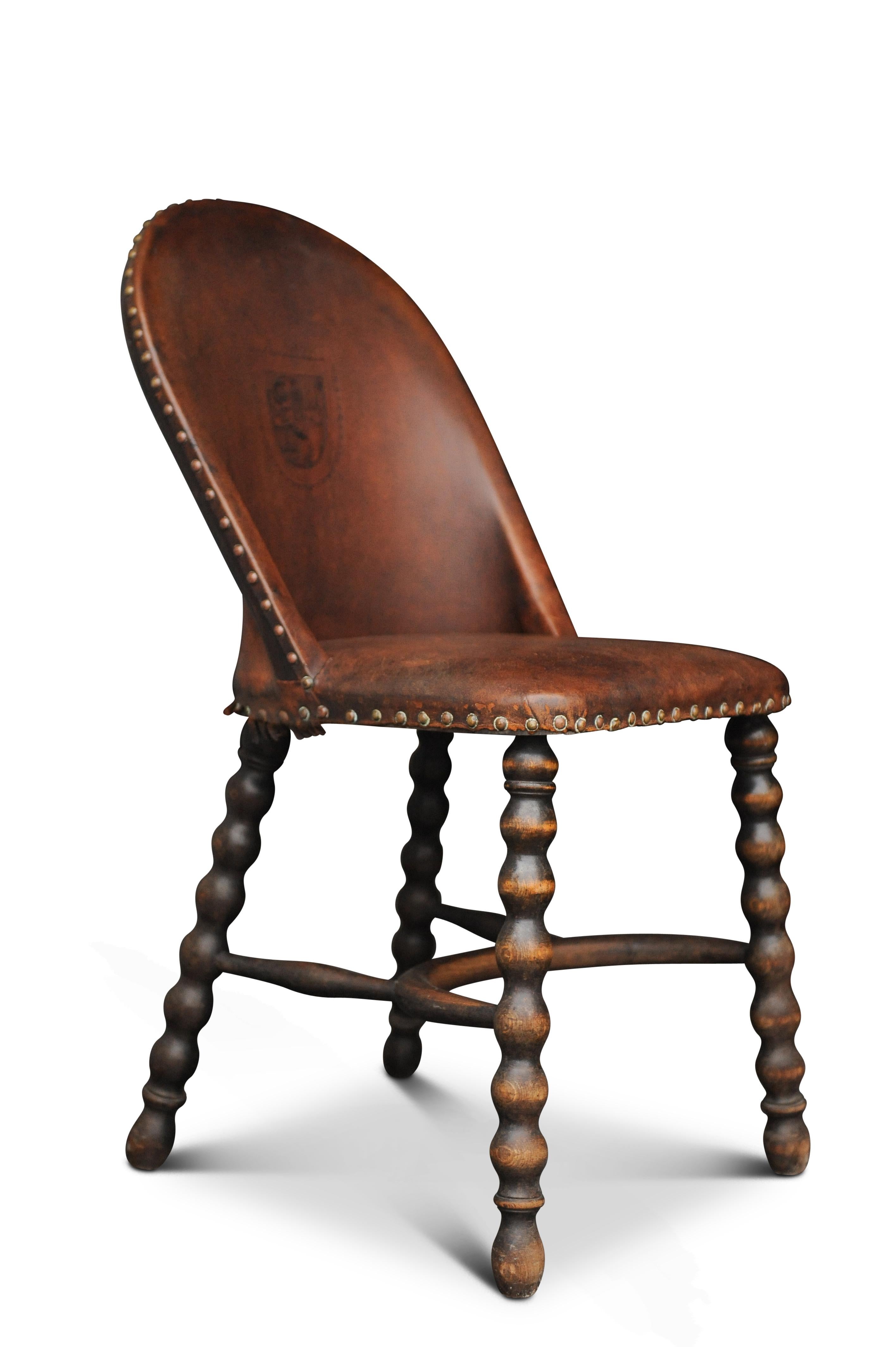 Ancienne chaise victorienne anglaise en acajou et cuir tapissée aux fuseaux, décorée d'un lion aux armoiries héraldiques estampées

Montée sur des pieds tournés aux fuseaux avec une civière à crinoline
