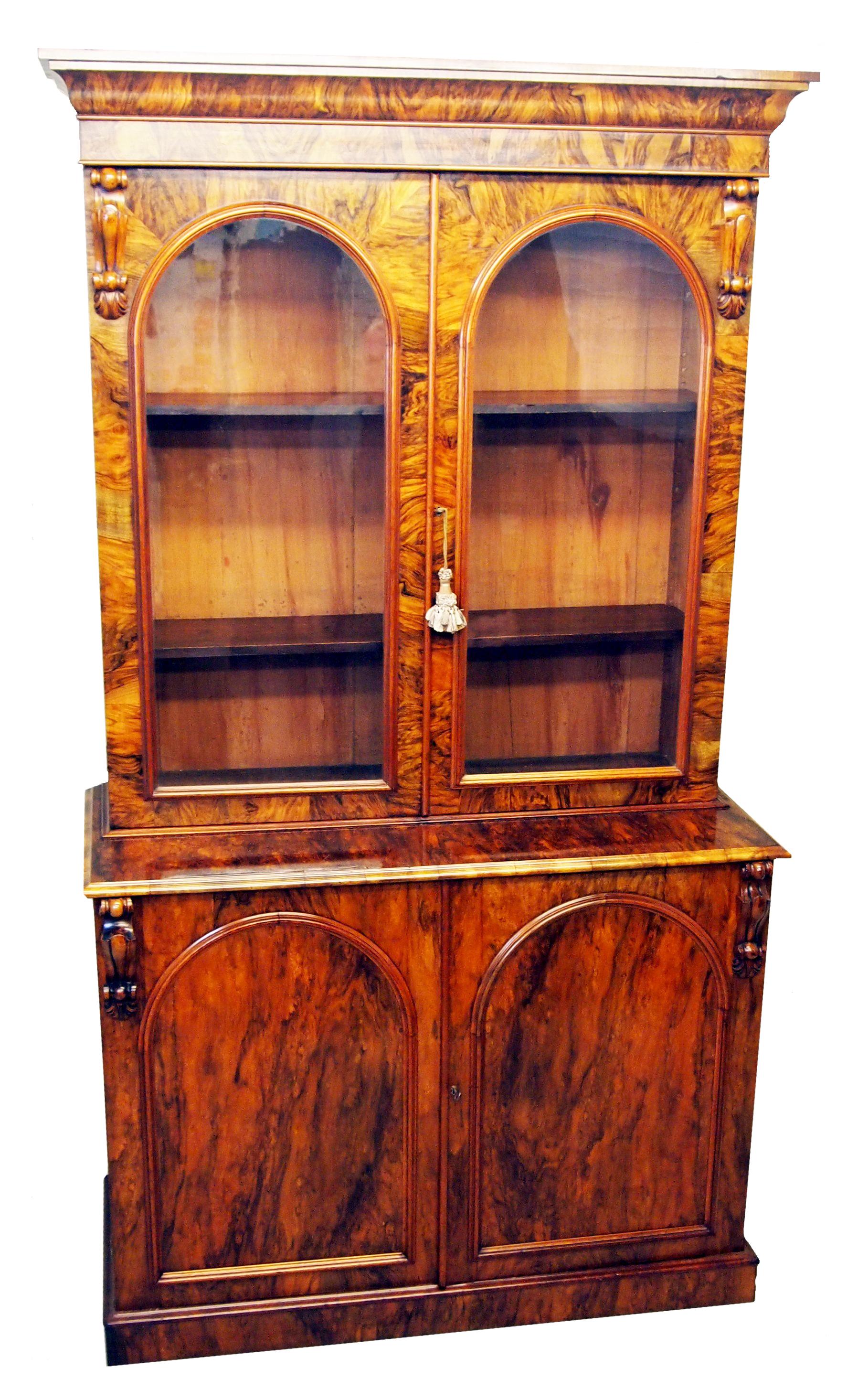 A Delightful Mid 19th Century Victorian Burr Walnut 
Library Bookcase Having Pair Of Glazed Doors To Top 
Part Enclosing Adjustable Shelves Above Arched 
Panelled Doors To Base Flanked By Carved Decoration
Raised On Original Plinth Base

( An