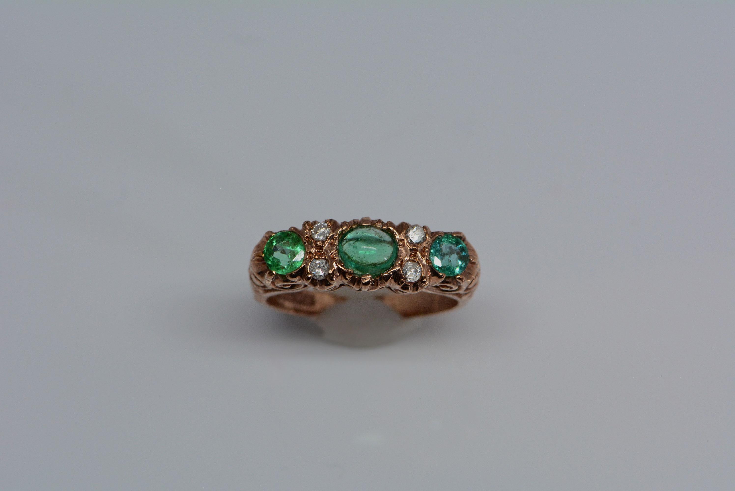 You'll find yourself lost in the details of this exquisite english ring: the vivid red tone of the hand-carved rose gold band against the emeralds is pleasing to the eye.

The ring has a total of three emeralds serving as the center stones, which