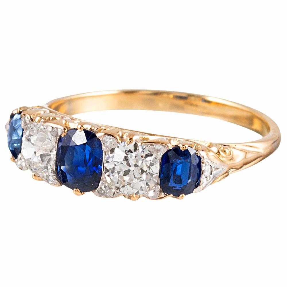 This celebrated classic is a staple piece for many antique jewelry collectors. This ring is made of 18 karat yellow gold and set with three cushion cut sapphires (1.25 carats in total) and two old European cut diamonds (1 carat in total). The