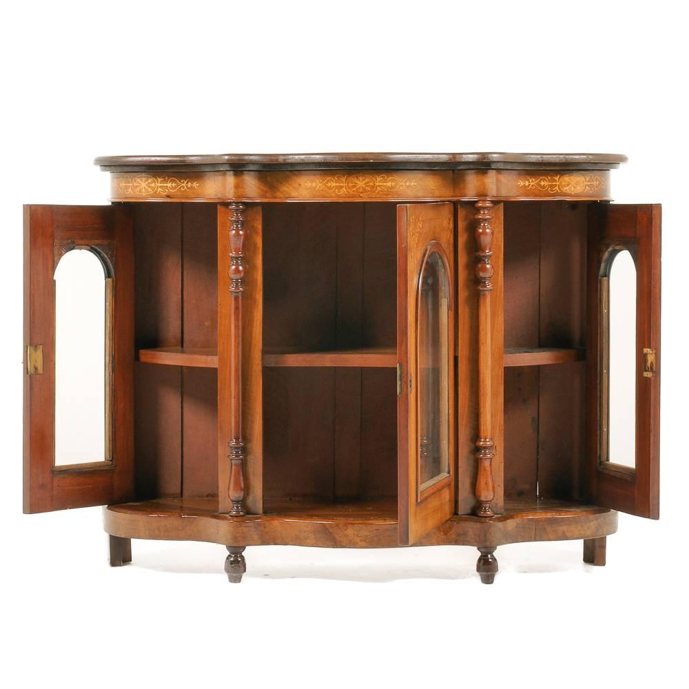 A Victorian English, inlaid walnut side cabinet of serpentine form, having three glass arched-top doors and an inlaid top, circa 1910.

     