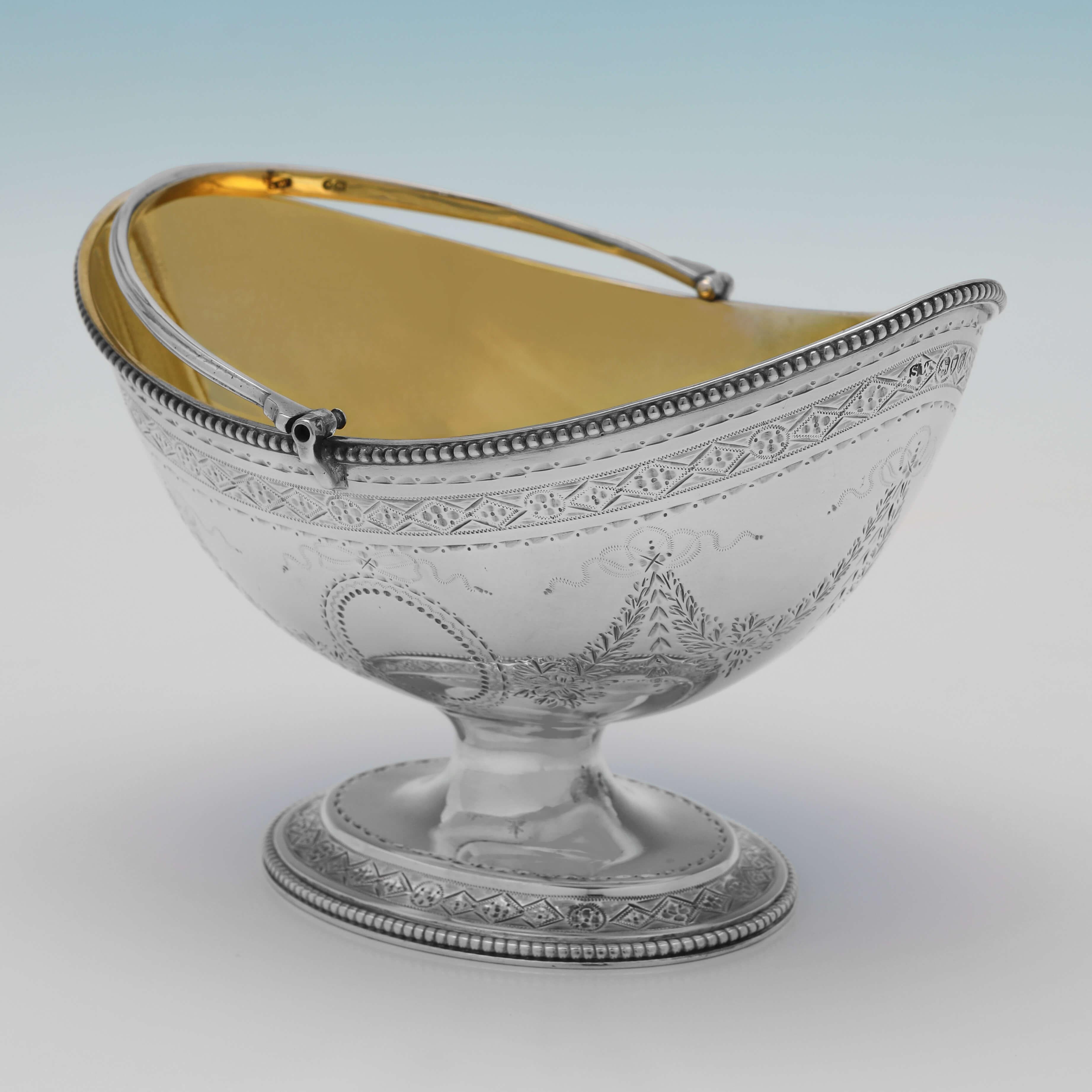 Hallmarked in London in 1882 by Samuel Whitford II, this very attractive, Victorian, Antique Sterling Silver Sugar Basket, features bright cut engraved decoration to the body and foot, bead borders, and a gilt interior. 

The sugar basket measures