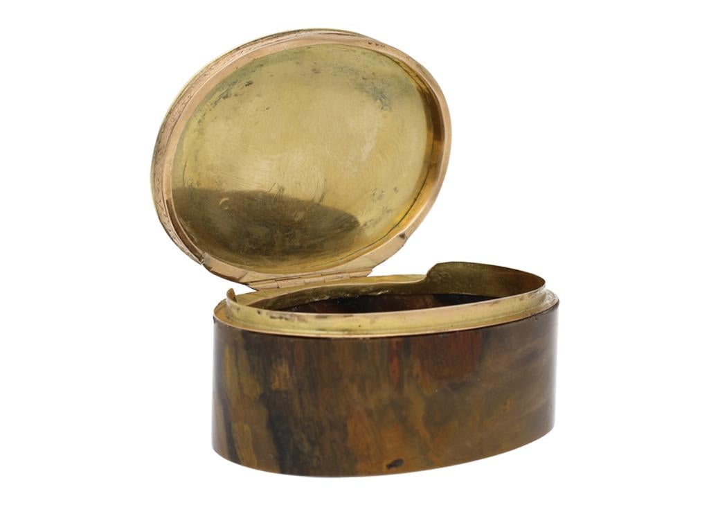 Victorian engraved box. An oval snuff/pill box featuring a gold lid engraved with floral motifs set within a garland border and a foliate pattern to the side, all on a petrified wood base, fitted to back with a secure hinged mechanism, the box