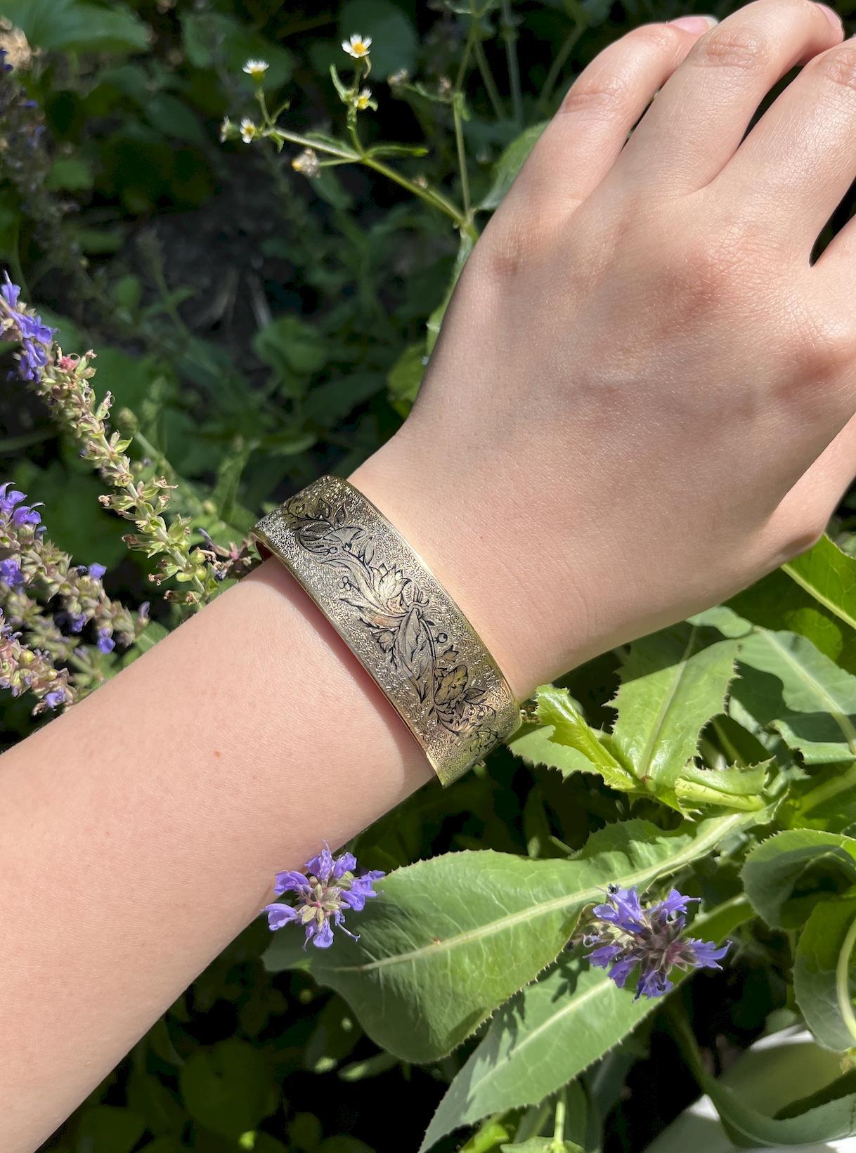 Bracciale vittoriano con smalto inciso in oro 14K
Fabrice a mano in oro 14 carati, questo braccialetto vittoriano con cerniera è impreziosito da una texture incisa a mano e da una graziosa vite fiorita che si snoda per tutta la sua lunghezza insieme