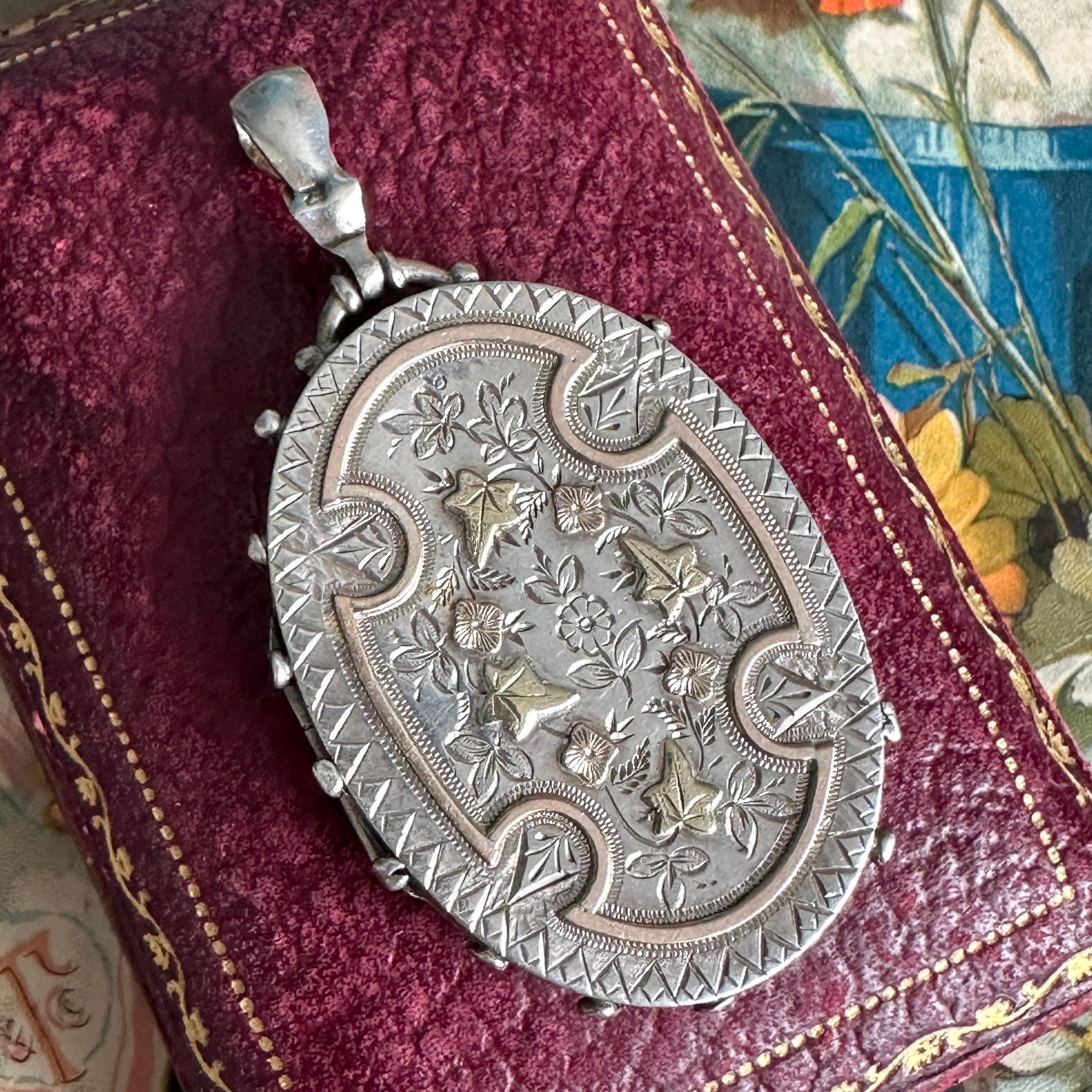 **Locket Only** 
(chain available separately) 

Details:
Victorian Aesthetic Movement large ornate silver locket, with sweet two-tone details. A beautiful silver and rose gold engraved abstract pattern and beaded details adorn the front of the