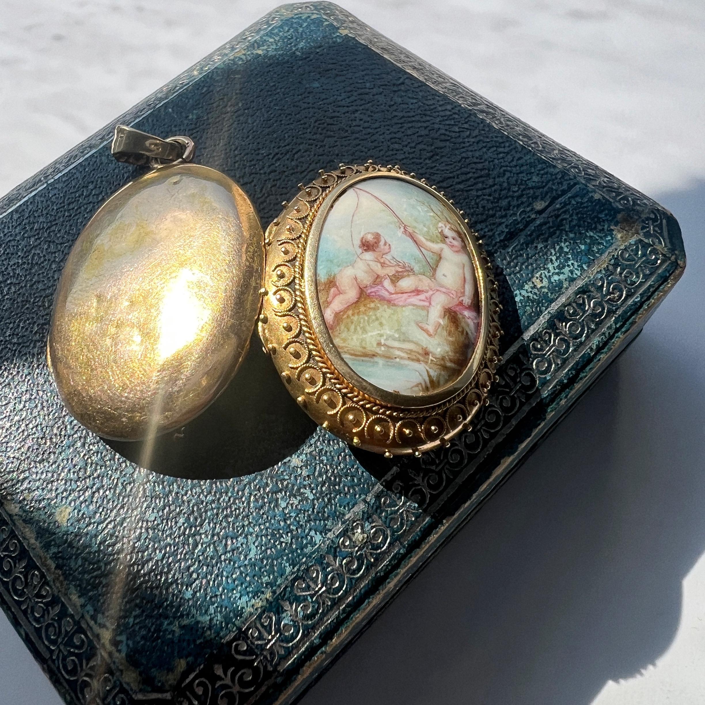 For sale a Victorian era 18K yellow gold photo locket, a treasure imbued with nostalgia and sentimental charm. This locket pendant features a captivating design centered around two enamelled cherub miniatures, gracefully engaged in a playful scene
