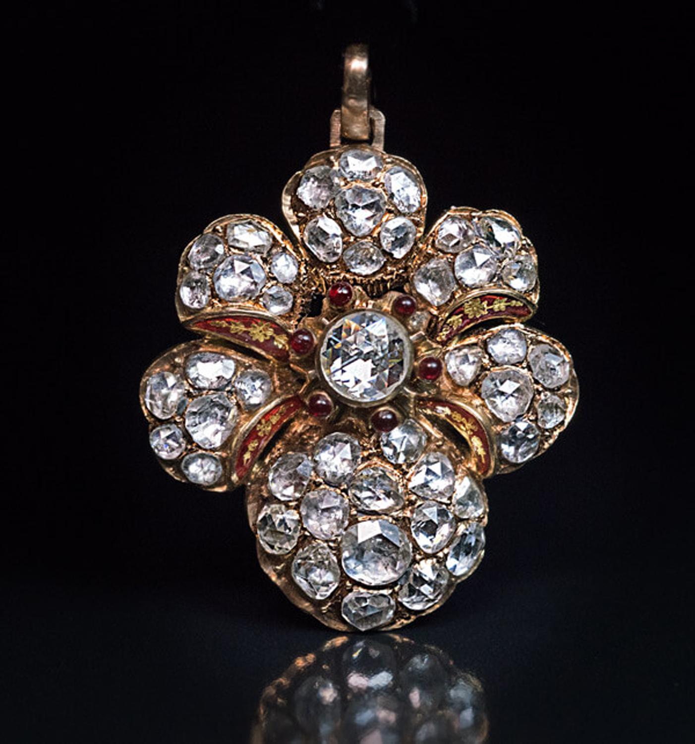 vers 1870
Ce pendentif en or en forme de fleur stylisée antique est densément serti d'environ 7 carats d'étincelants diamants taillés en rose de différentes formes et tailles. Les pétales sont séparés par de l'émail rouge bordeaux peint de motifs