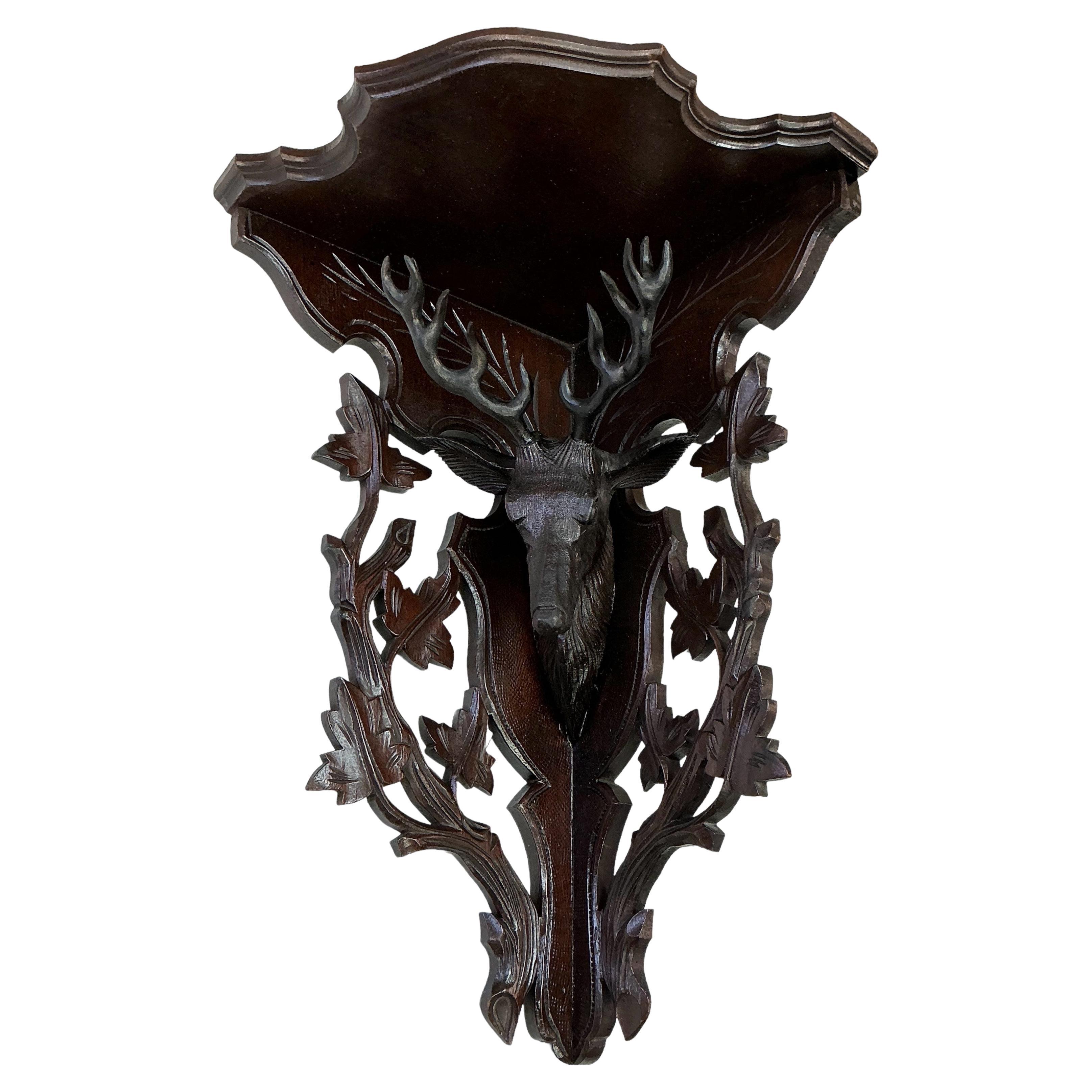 This is a Victorian Era Black Forest style carved corner shelf with a centered deer bust. It is framed with carved branches and leaves. It is most likely American and is unmarked.