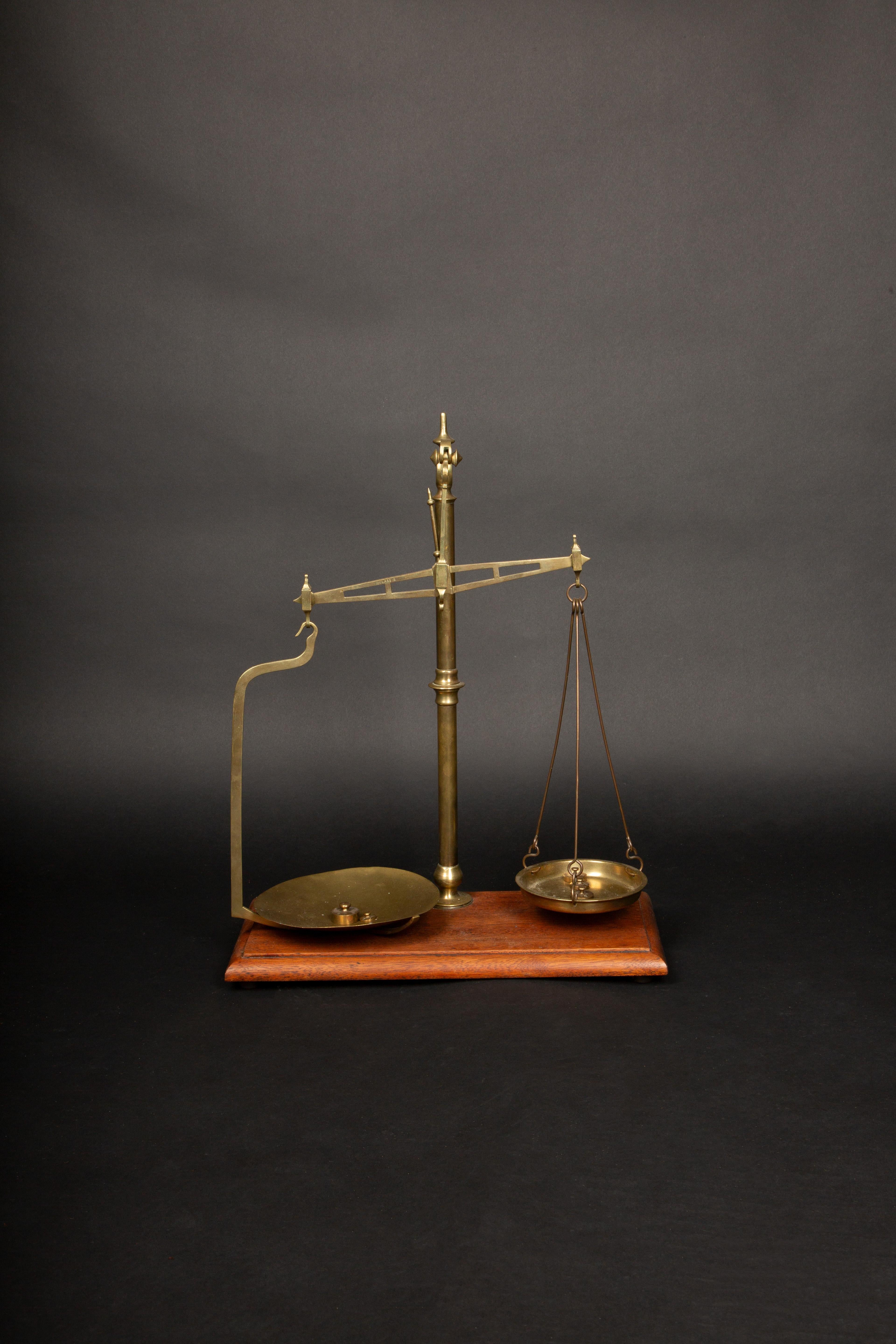 This elegant brass balance scale dates back to the late 19th century, a period marked by the precision and craftsmanship of Victorian England. The scale is meticulously crafted from solid brass, showcasing a beautifully aged patina that highlights