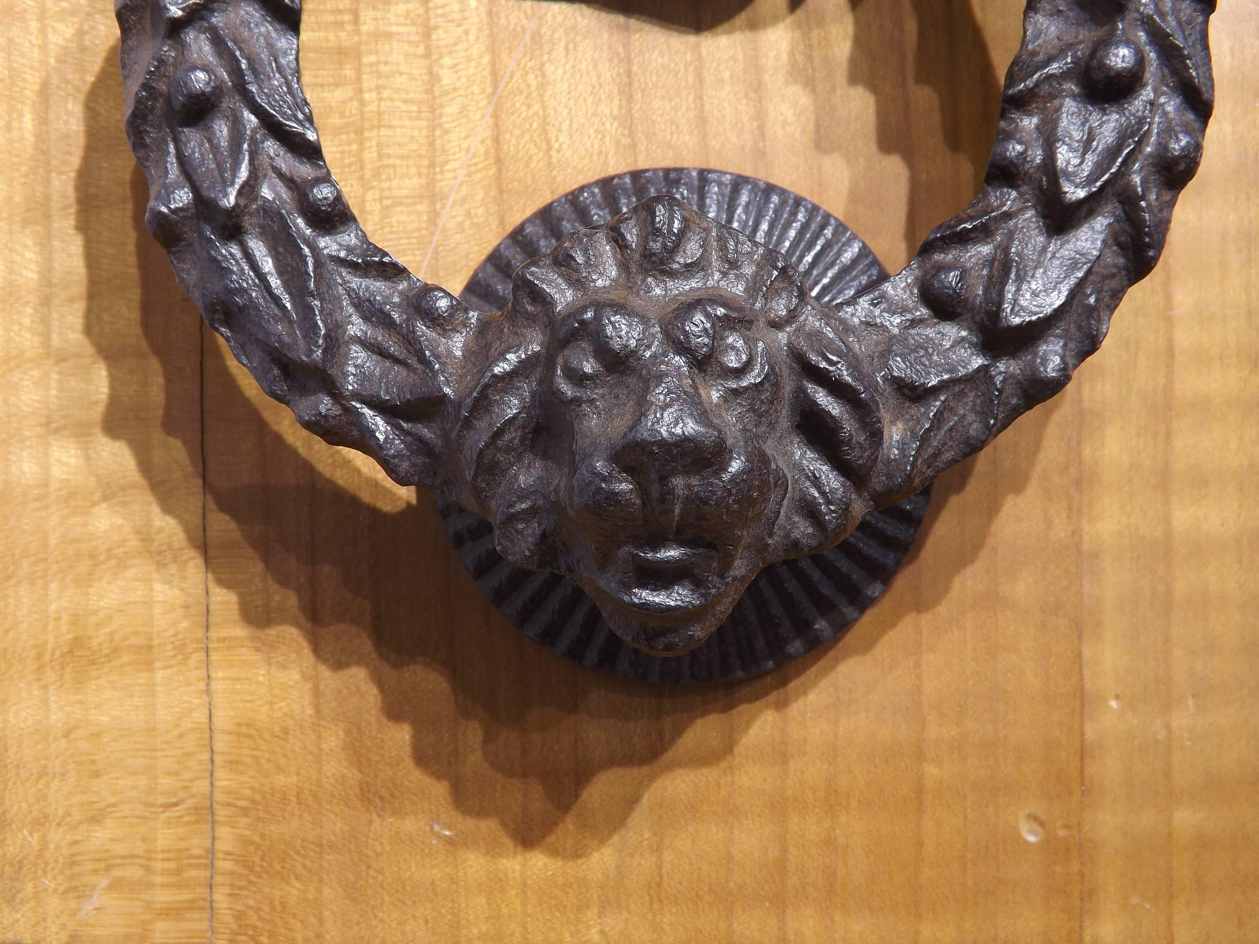 A handsome Victorian Era door knocker of a clenched fist holding a wreath with a lion's head. Complete with matching hammer plate, mounted on a wooden board for display. Easily adapted for use on a modern door. Knocker dimensions are 6 inches tall,