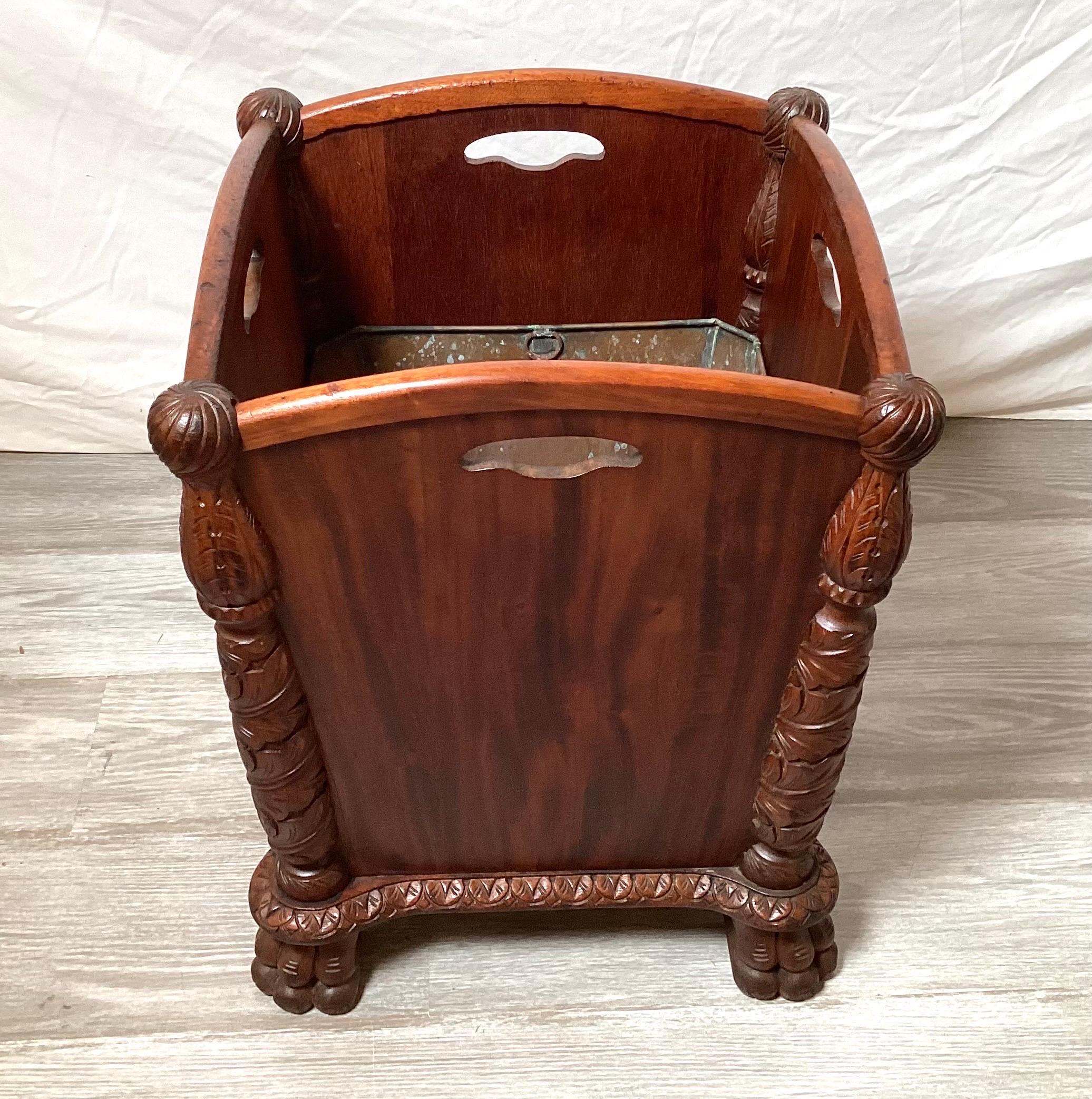 An ornately carved Victorian era waste basket with copper lining, The curved form with lion paw feet with 4 carved in hand grips. The wood is flame mahogany , 18 inches tall, 14 inches square.
