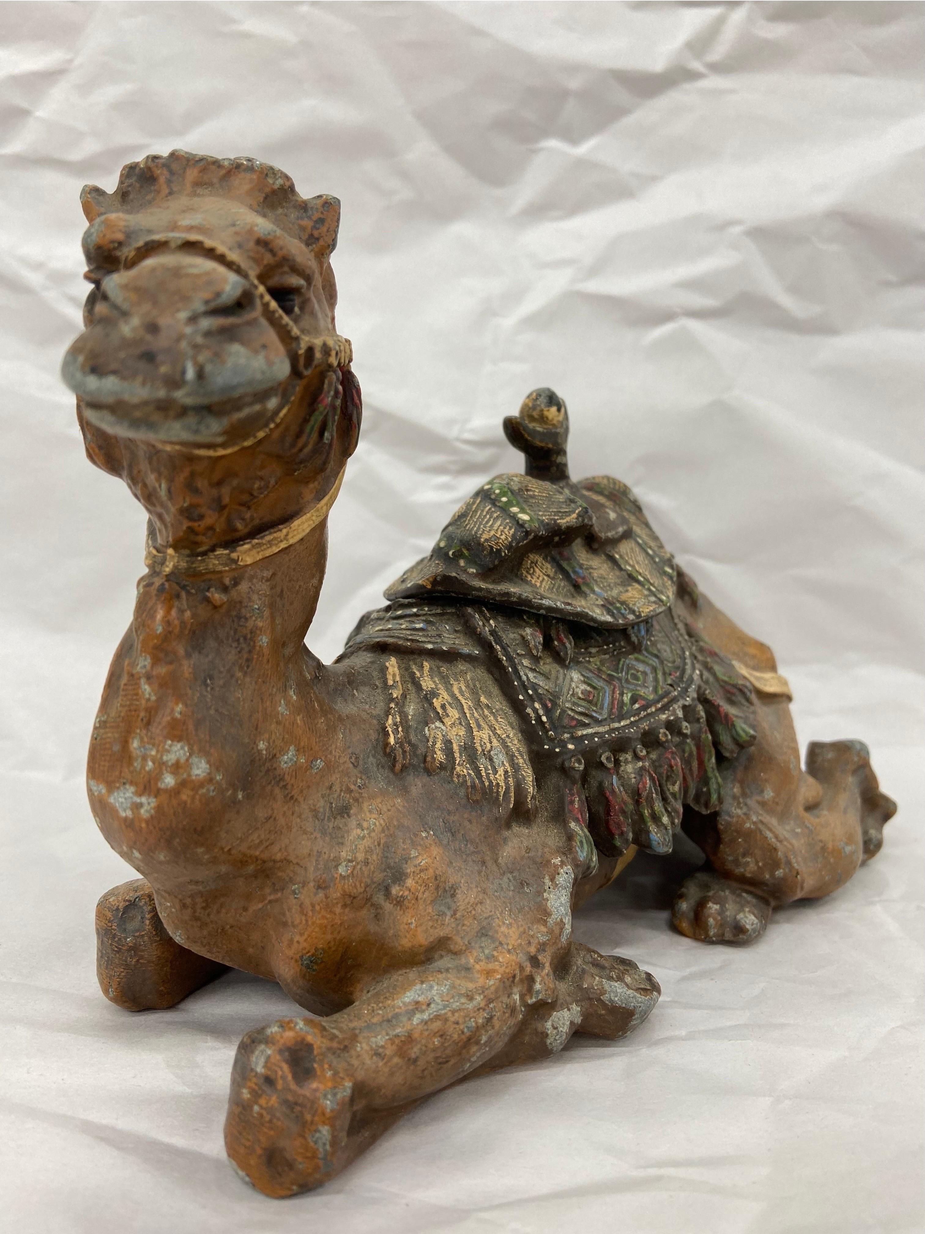 A Victorian Era, circa 1900, antique cold painted spelter (smelted and alloyed zinc) figural and sculptural inkwell depicting a seated camel. The realistically portrayed camel is shown with a highly detailed saddle. The camel is also portrayed with