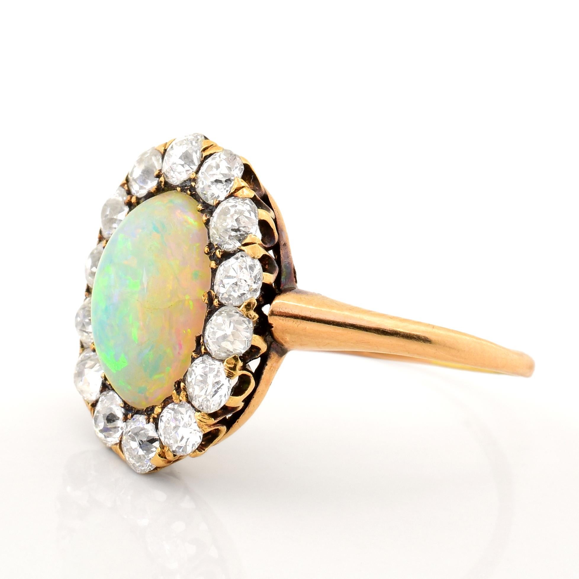 A Victorian Era ring featuring an oval cut Opal center stone. The Opal is white in color, with vibrant yellow, green, and orange marbled throughout the stone. The Opal is surrounded by rose cut diamonds. The yellow gold has a beautiful patina over