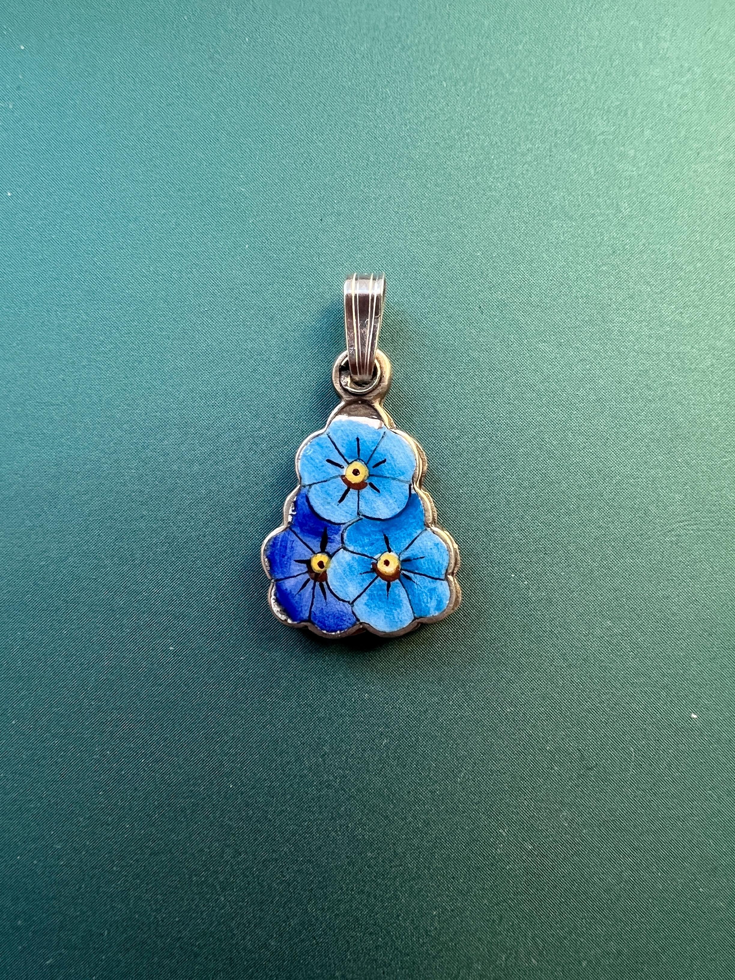 In front of us a very rare and lovely antique pendant: It features three blue enameled pensy flowers with yellow heart.  You can slide the pendant to discover what’s hided inside of the pendant, it is written “ ne m’oubliez pas”, which means “ do
