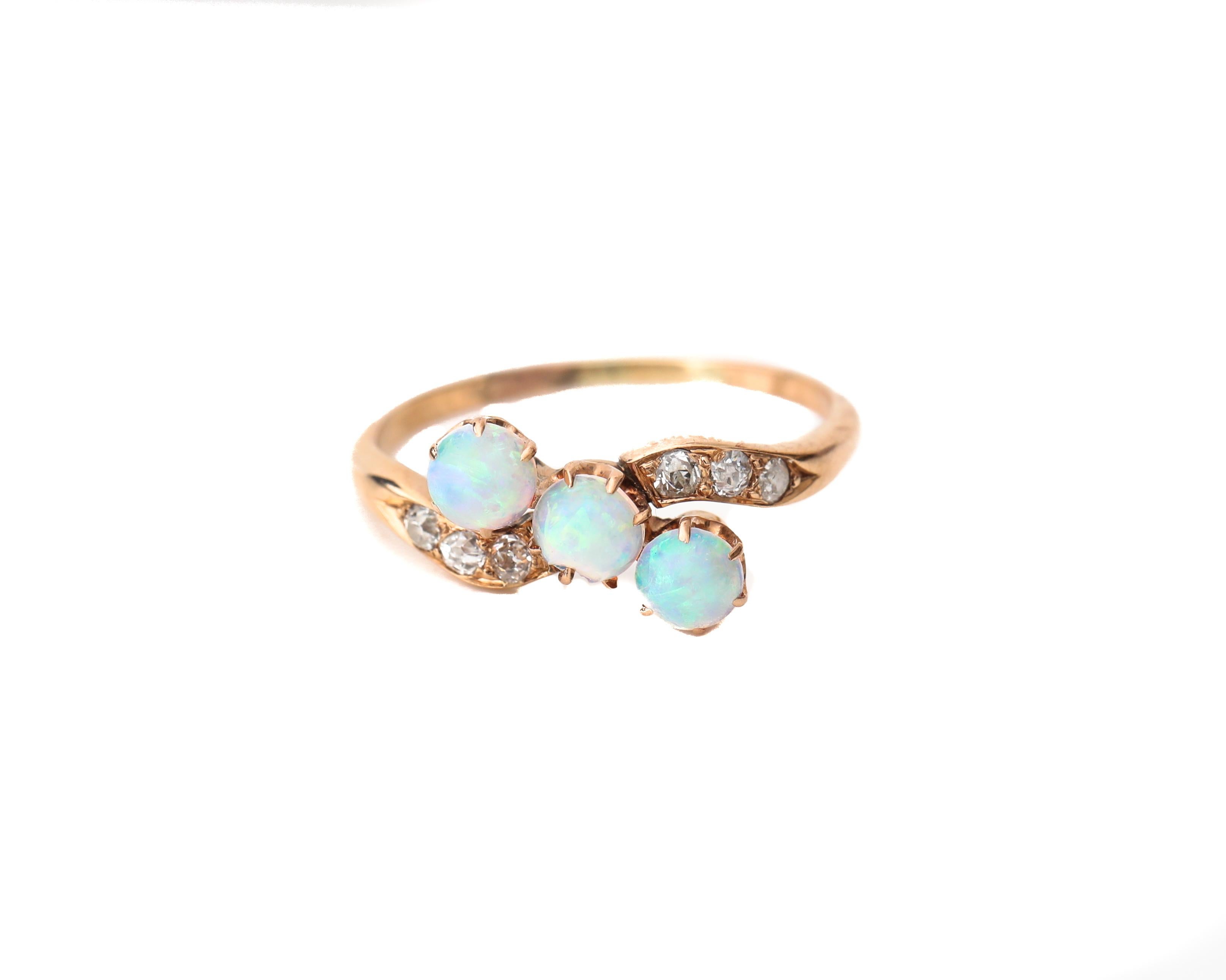 This genuine Victorian piece is crafted with a beautiful rose gold band that has 3 round shimmering opals. The ring has talon prongs that hold the opals perfectly displaying all color stone and less metal. There are also 6 accent diamonds, 3 per