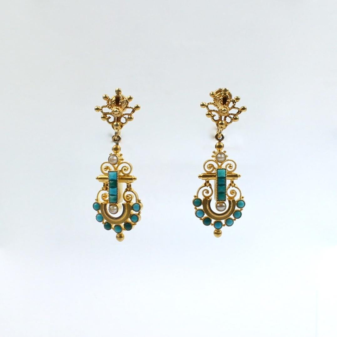 A very fine pair of Victorian Etruscan Revival screw-back dangle earrings in 14k gold.

The earrings have both filigree decoration and granulated and wire work decoration. They are bezel set with small turquoise cabochons and seed pearls and each