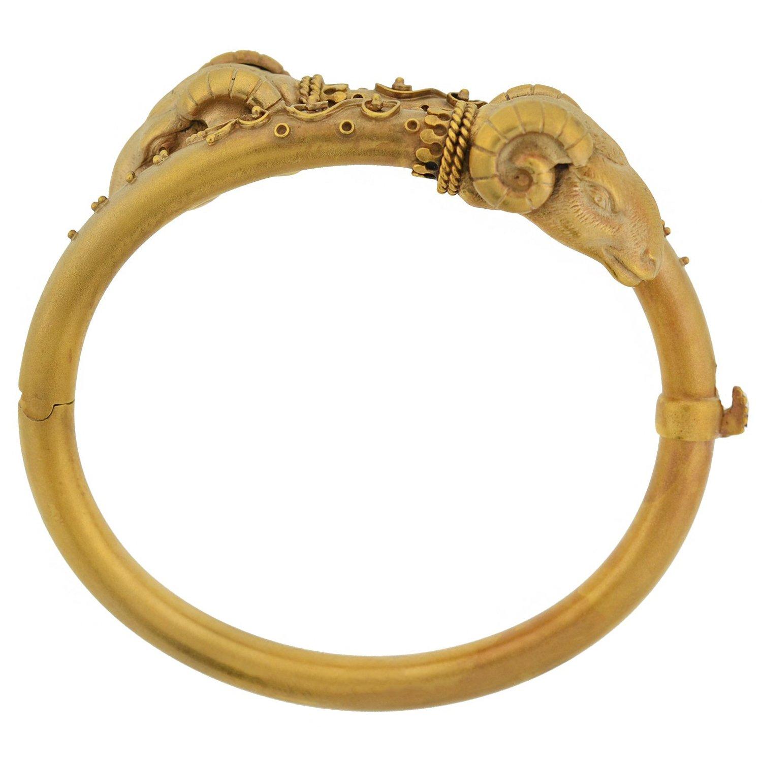 An impressive statement bracelet from the Victorian (ca1880) era! Crafted in 14kt gold, the bangle incorporates a double ram's head motif into a stylish bypass design. Each 3-dimensional ram's head is incredibly detailed, including curling horns,