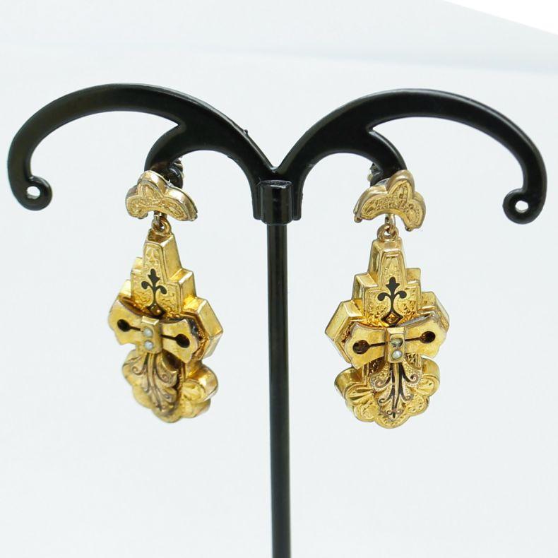 Viktorianisches Paar Ohrringe aus Draht. Die Ohrringe aus 10-karätigem Gelbgold haben eine Länge von ca. 3 cm und sind mit schwarzen Emaille-Blättern und -Rollen sowie kleinen Perlen verziert.
Etruskische Vintage-Ohrringe:  Viele Juweliere des