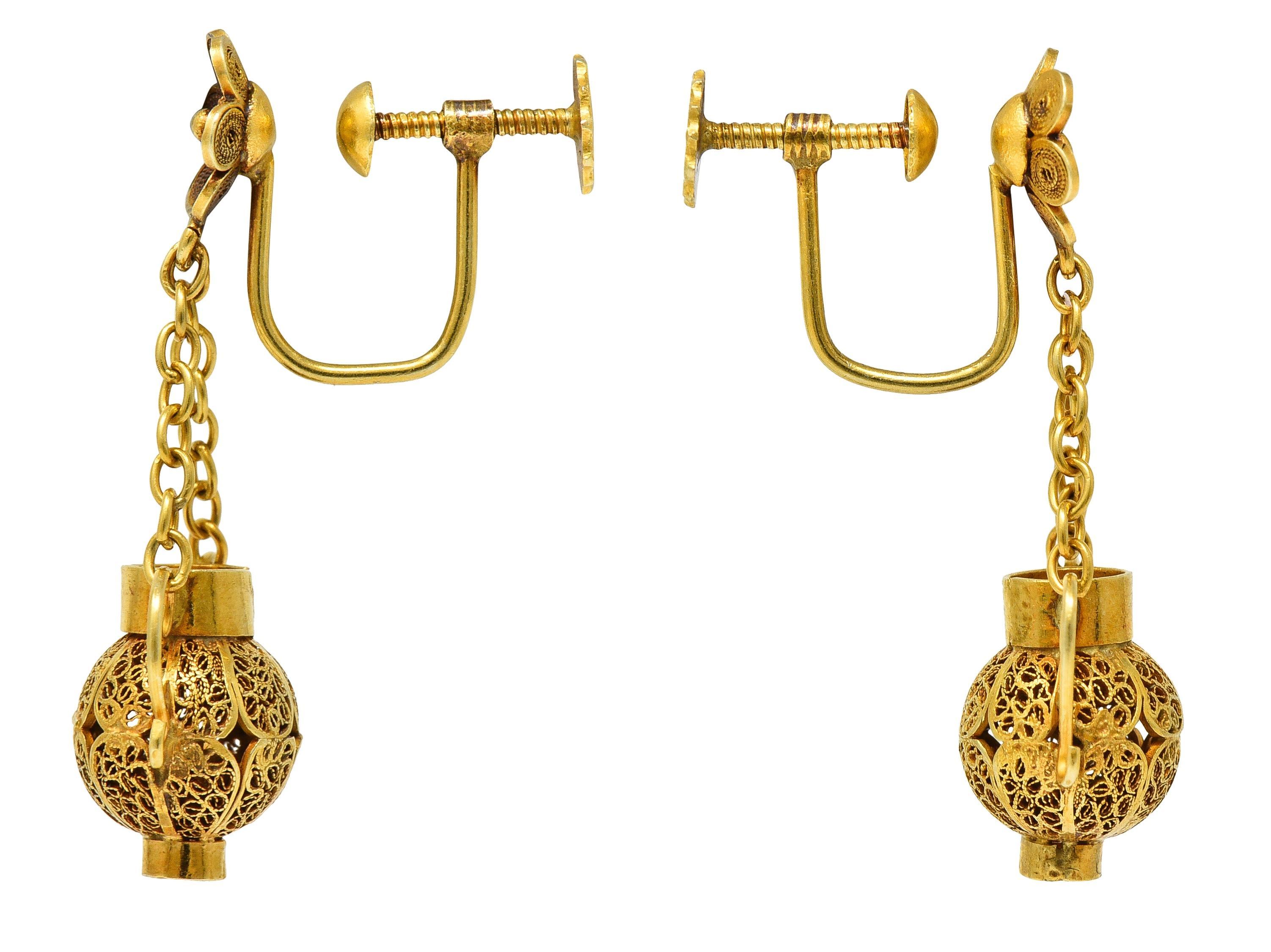 Comprised of floral surmounts with curling filigree petals suspending drops via cable chain
Drops are designed as stylized amphora vases
With filigree body and scrolling wire handles
Completed by screw-back closures
Tested as 18 karat gold
Circa: