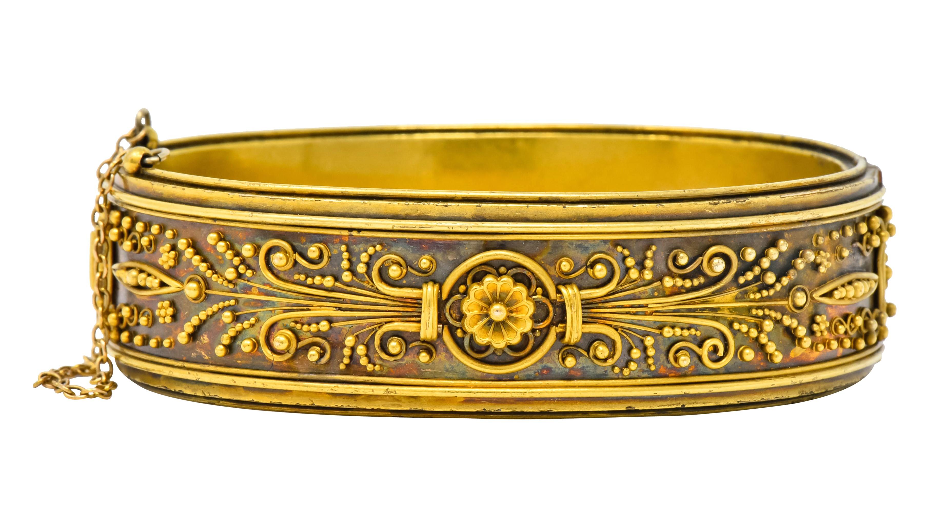 Bangle style bracelet centering a scalloped flower on each side flanked by stylized wheat motif

With deeply grooved edges and gold bead detail throughout

Hinged with concealed clasp and safety chain

With dated inscription

Tested as 14 karat