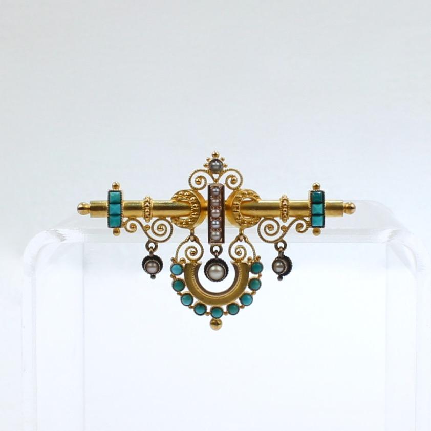 A very fine Victorian Etruscan Revival brooch.

In 14k gold with both filigree decoration and granulated and wire work decoration throughout. It is bezel set with small turquoise cabochons and seed pearls.  

Suspended from the top bar is an arc