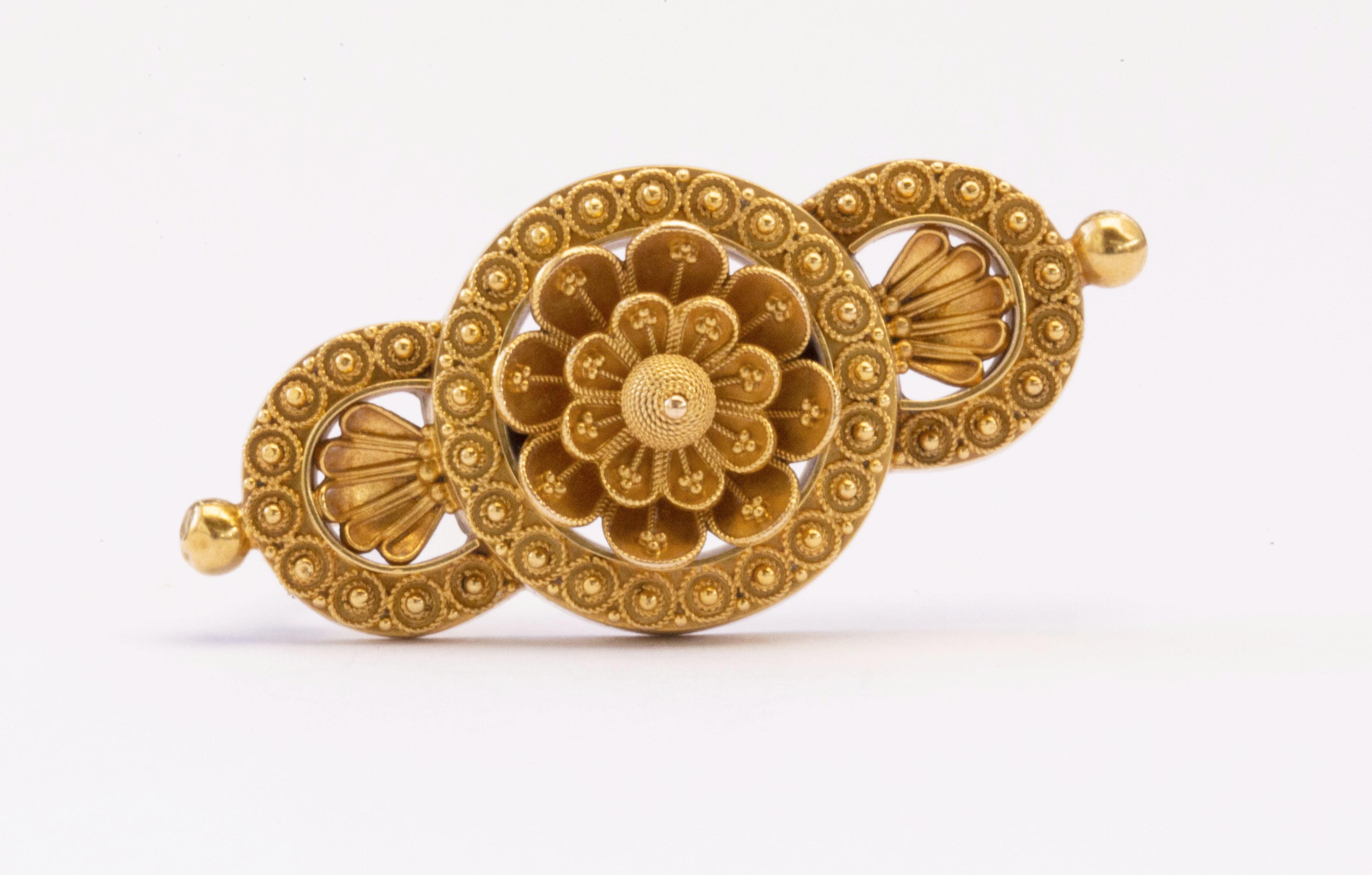 An antique Victorian English 15 karat yellow gold brooch in Etruscan Revival/ Neo Etruscan style that was characteristic from the jewelry from the Victorian Epoche in the late 19th century. The brooch features fine filigree and granule decoration