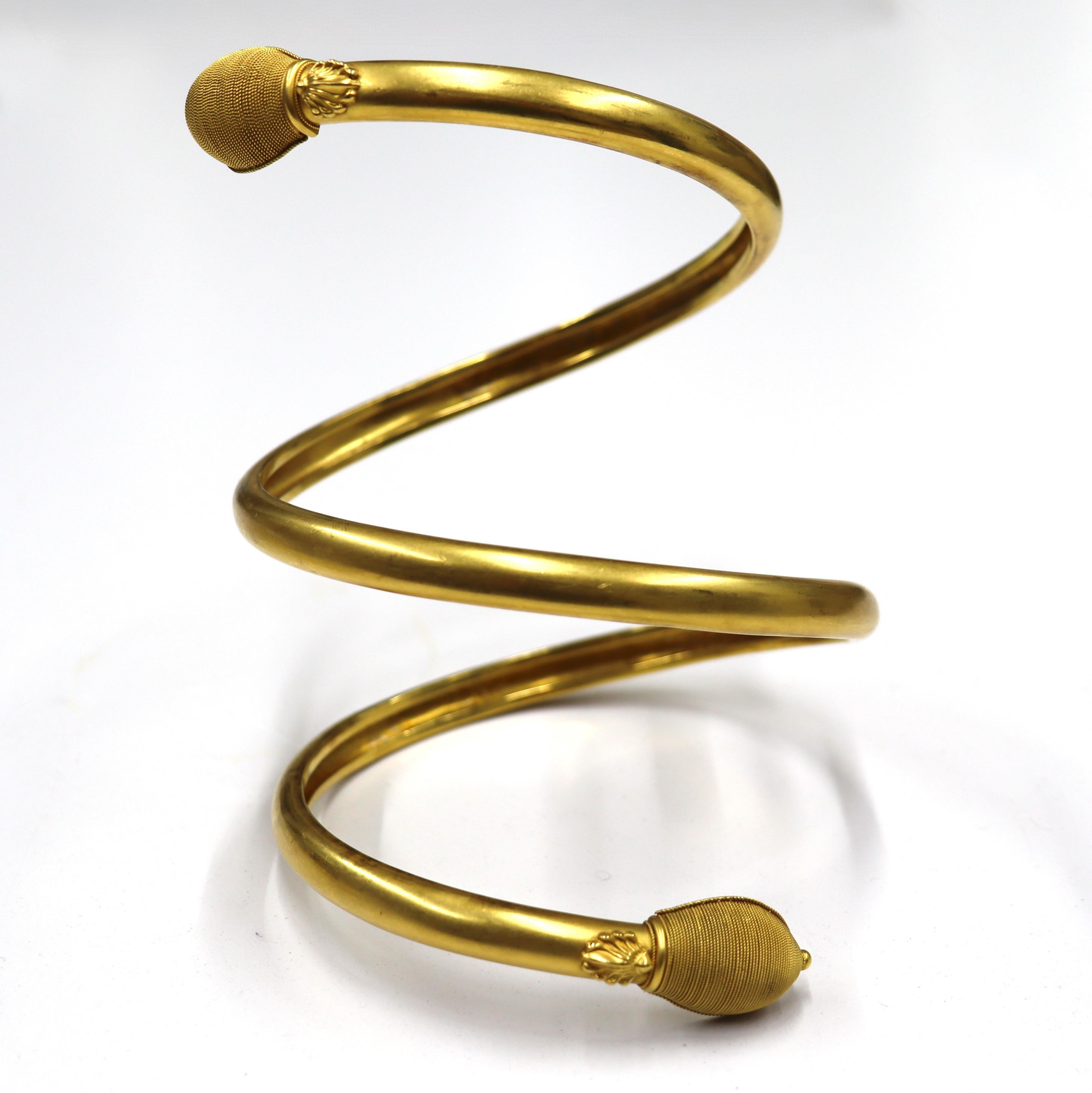 Un brassard en or de style néo-étrusque de l'époque victorienne,

vers 1880.

Rare brassard victorien de style néo-étrusque en or brossé 18 carats, s'enroulant trois fois autour du bras, les extrémités étant rehaussées de têtes de serpent stylisées