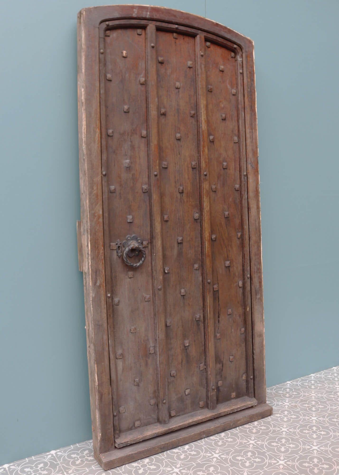 Cette épaisse porte en chêne clouté date du début des années 1900. Elle faisait peut-être partie de l'entrée d'un château ou d'une église. Quelle que soit son ancienne utilisation, cette porte ancienne avec cadre constitue aujourd'hui une porte