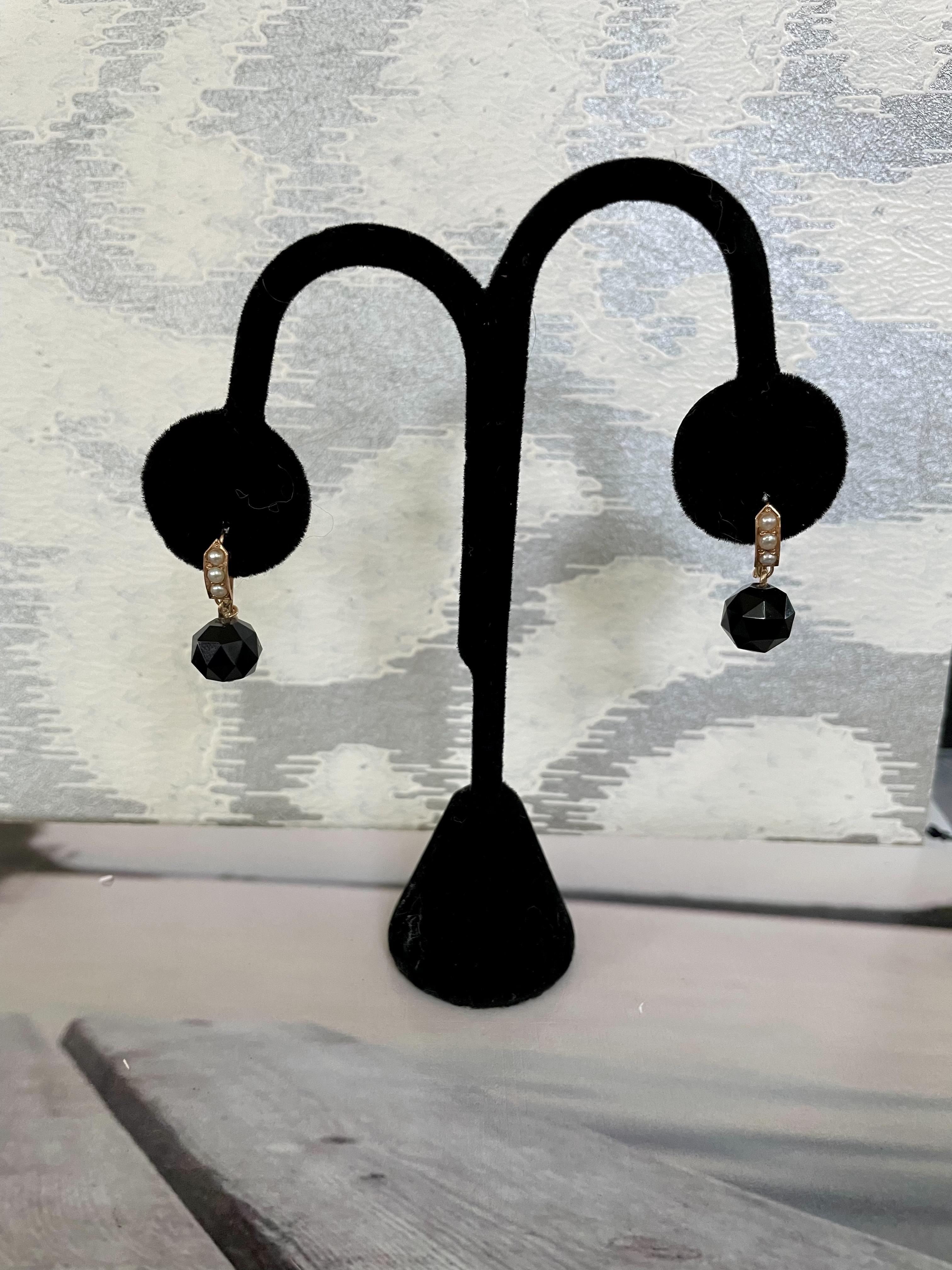 These Victorian earrings feature a faceted black Onyx stone which drops from the ear with a piece of 14 karat yellow Gold which has been accented with three seed Pearls.  

Weight:  3.7 grams
Measurement: 3/4