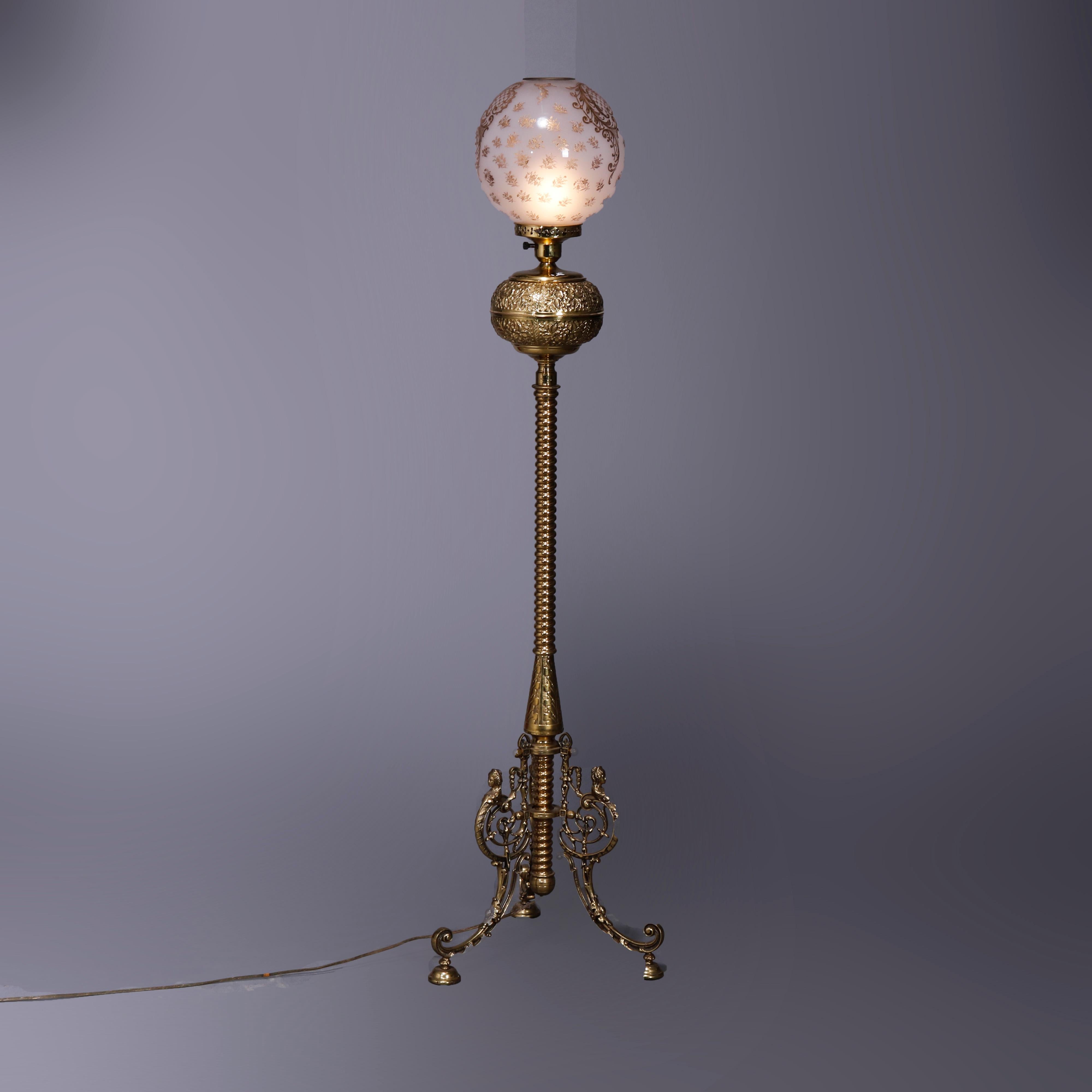 An antique Victorian piano lamp by B. Hollings & Co. offers gilt decorated glass globe shade over brass base having foliate embossed font and raised on three scrolled foliate legs, dated 1888

Measures - 58.25'' H x 15'' W x 15'' D.
