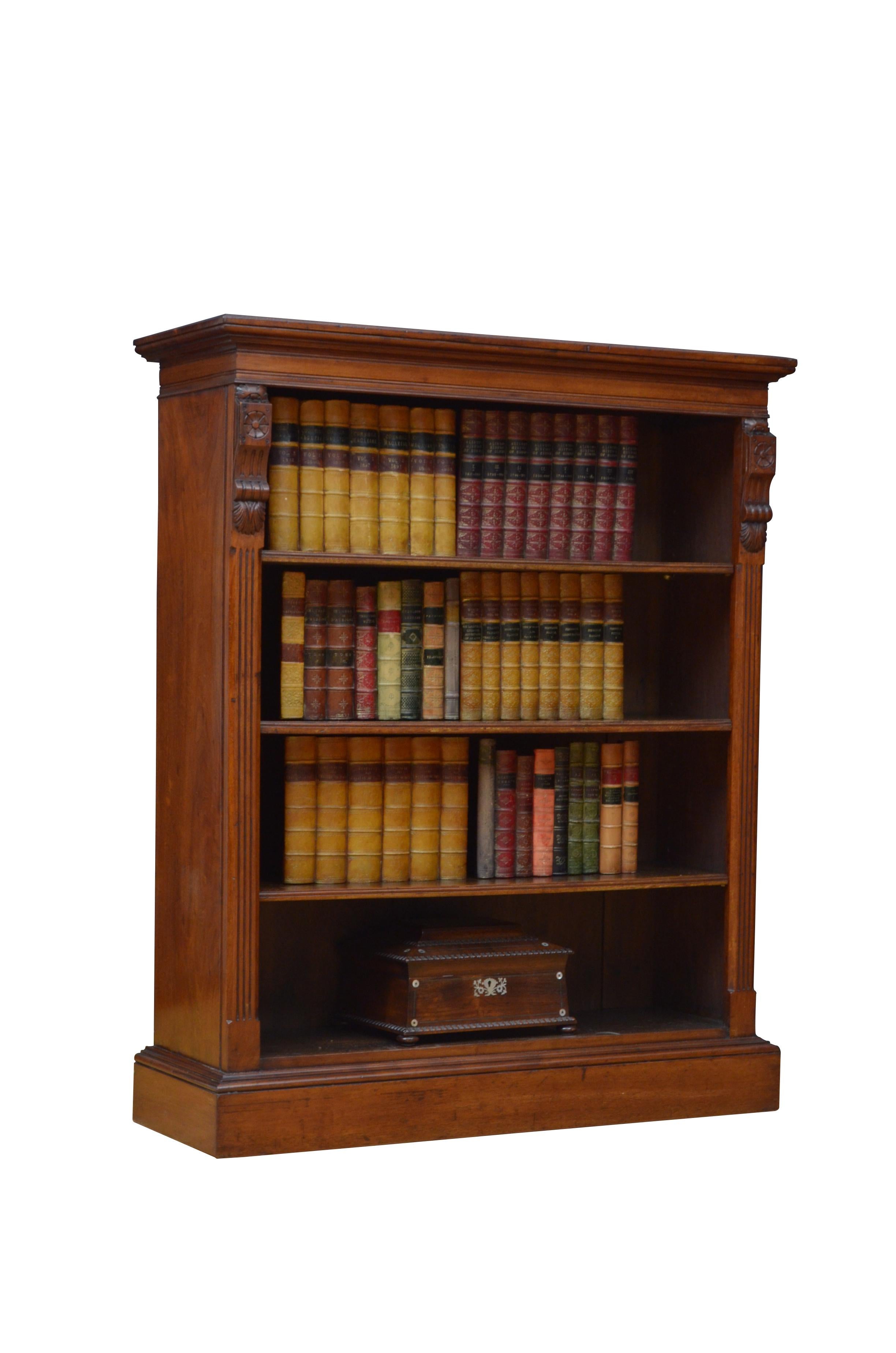 0587 Attractive Victorian open bookcase in solid walnut, having figured walnut top, moulded frieze and three height adjustable shelves, all flanked by fine drop carving and reeded pilasters, standing on moulded plinth base. This antique bookcase