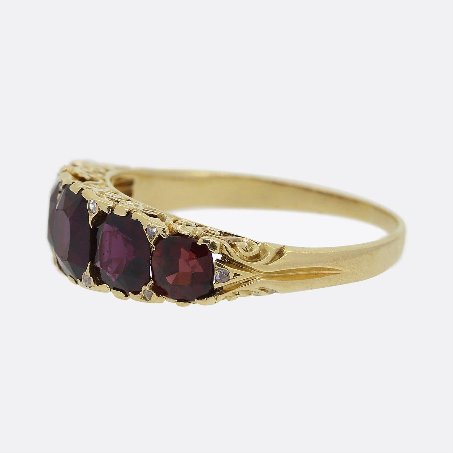 Here we have a 18ct yellow gold Victorian five stone ring. The piece showcases five square cushion cut garnets in a single line formation which graduate inwardly in size. Neatly nestled in between each focal garnet is a tiny rose cut diamond above