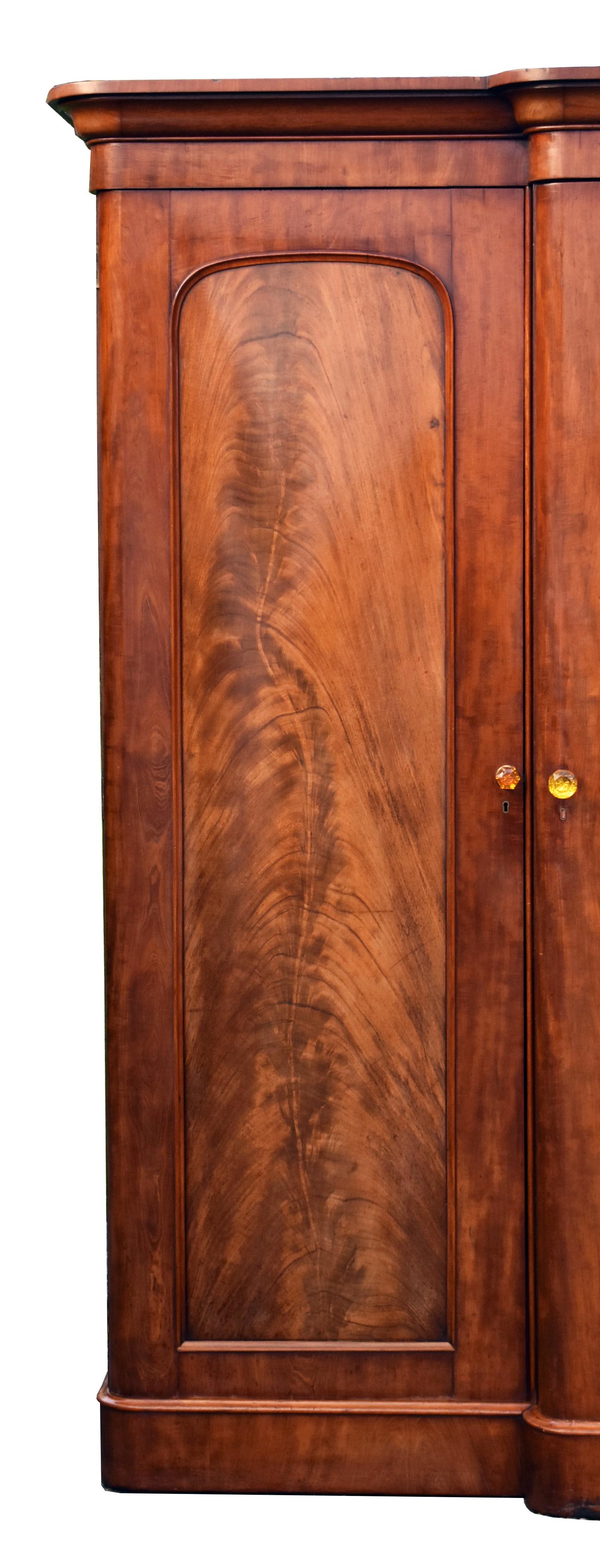 For sale is a good quality Victorian flame mahogany wardrobe, having a stepped and flared cornice, above three doors, the centre of which featuring a mirror, and opening to a fitted interior including trays and drawers. The wardrobe stands on a