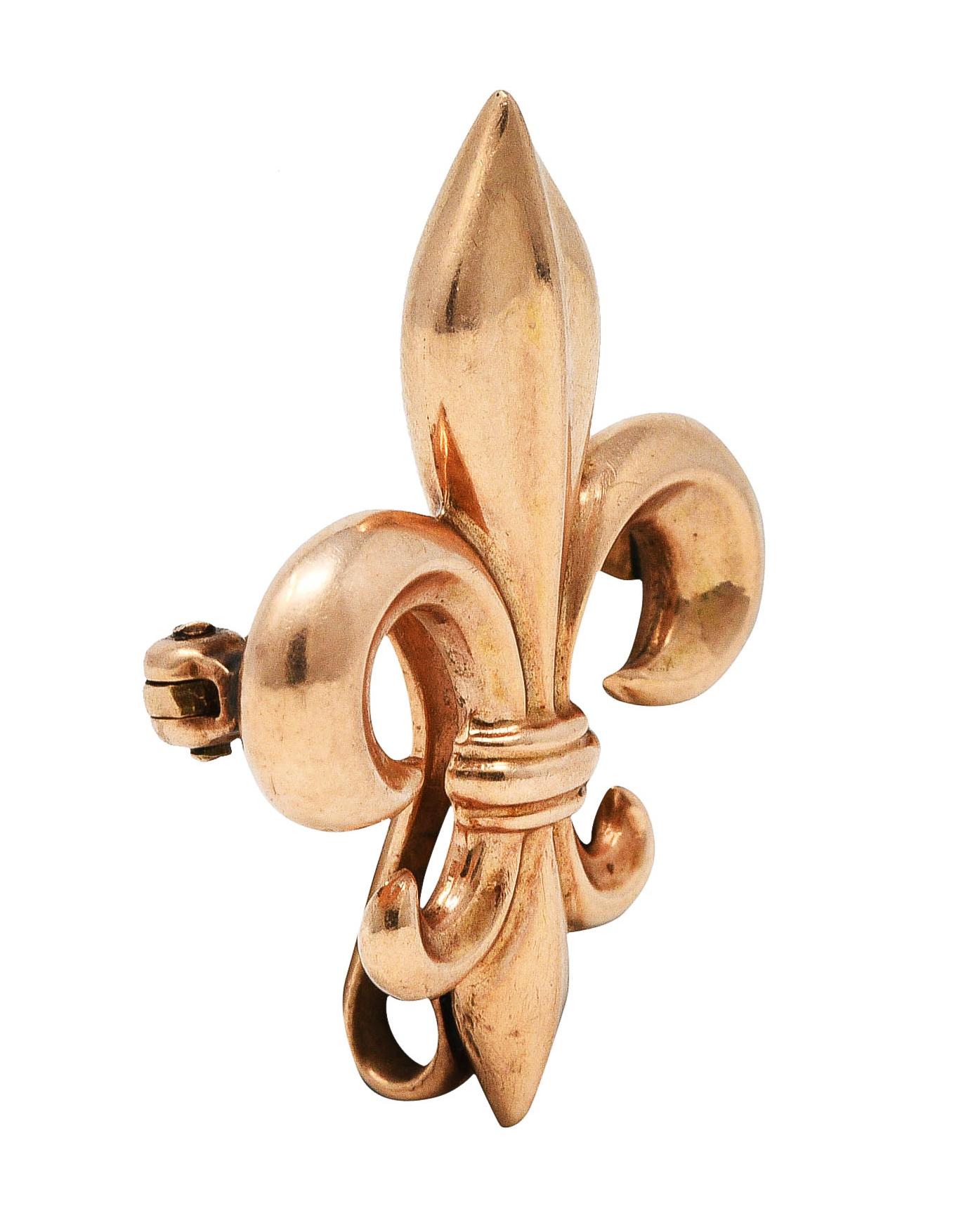 Pendant brooch designed as stylized fleur-de-lis

Featuring puffed gold form with grooved detailing

With hidden looped bale

Completed by pin stem with locking closure

Stamped 10k for 10 karat gold

Circa: 1890

Measures: 13/16 x 1 1/16 inches