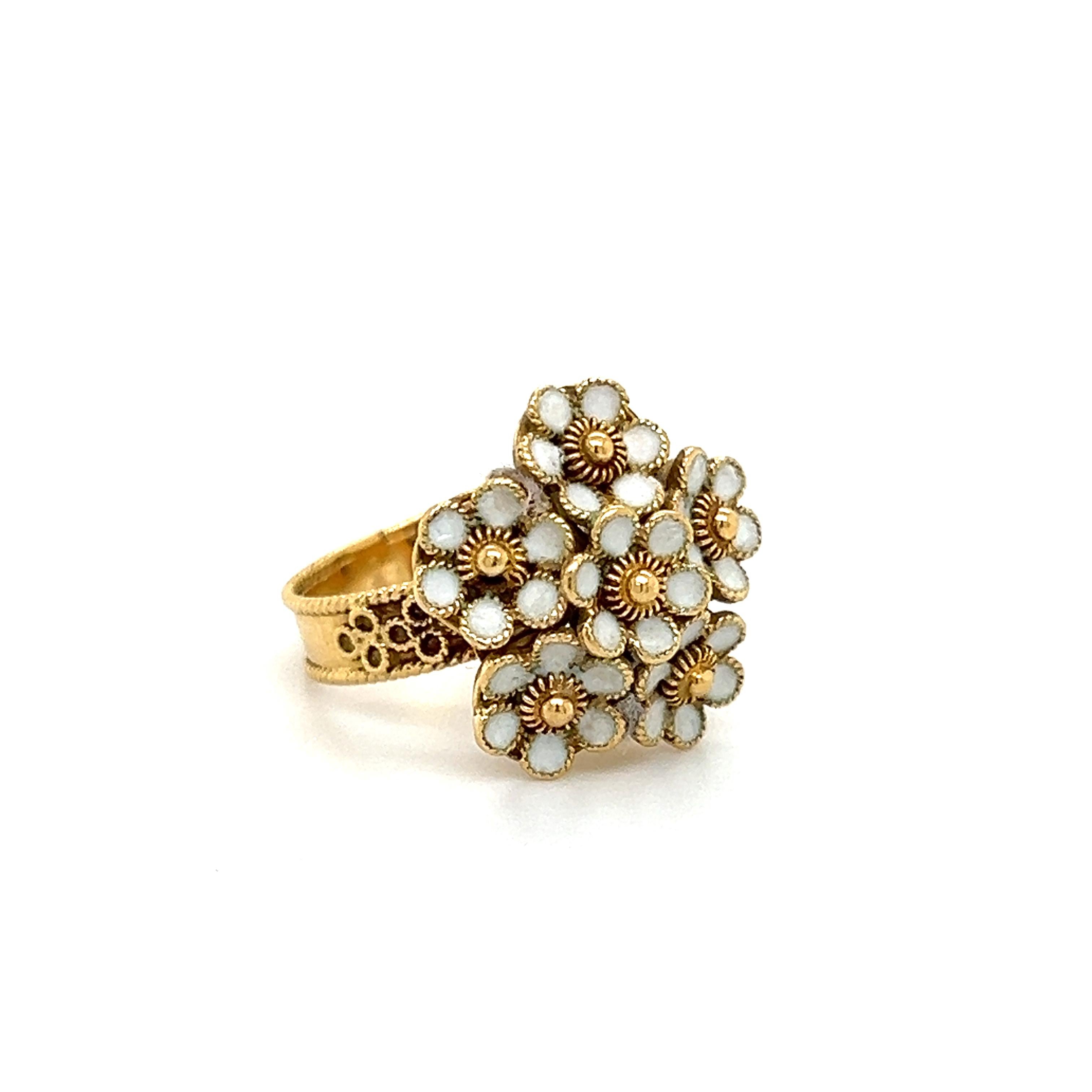 Beautiful ring crafted in 18k yellow gold. This vintage treasure is nearly 120 years old and was made in the Victorian era.
Details are endless as the ring highlights a floral bouquet, with white enamel decorating the petals. The enamel is in