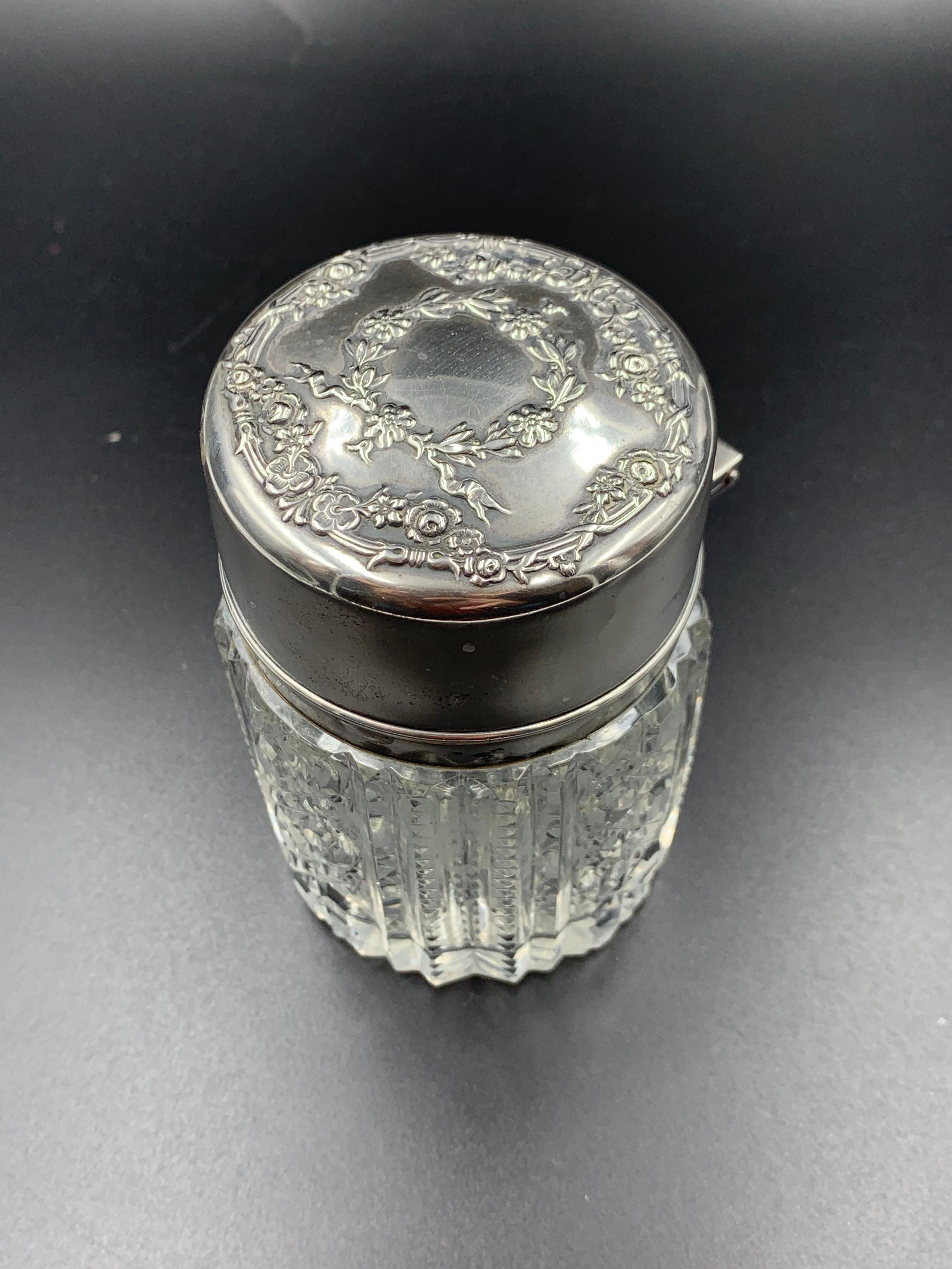 Antique Victorian dresser jar featuring a hinged sterling silver lid with a floral garland design mounted a beautiful cut glass bottle. Inside the hinged lid is an internal glass CAP to keep the contents fresh. It is marked Sterling with an 