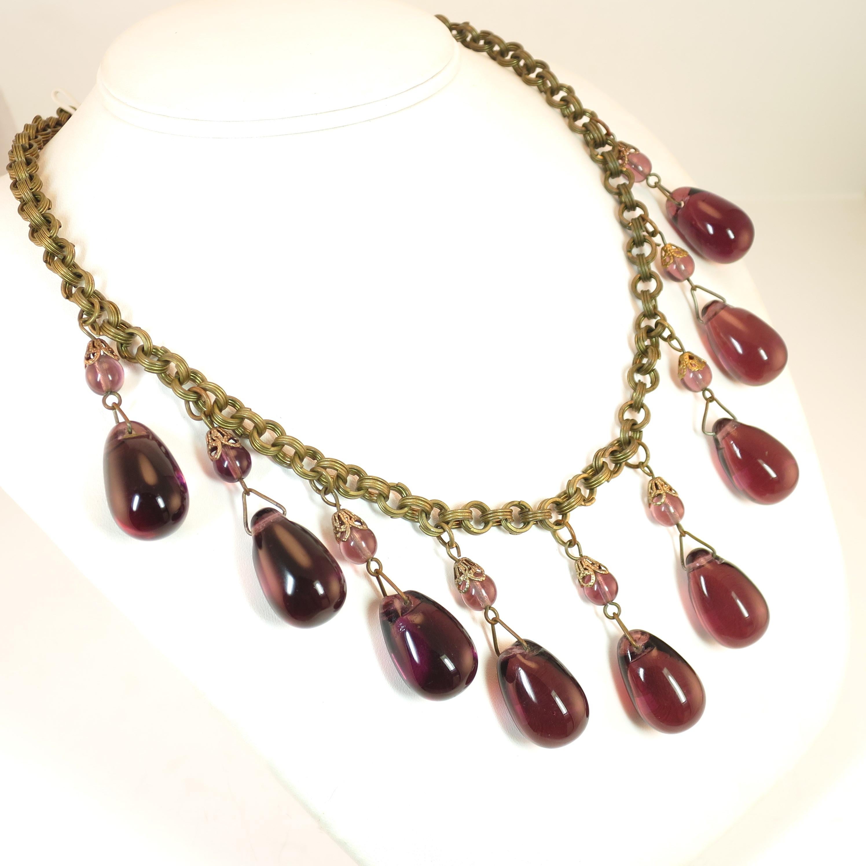 Offered here is a French Victorian heavy chain necklace with amethyst poured glass dangles from the 1870s. The gold-washed chain consists of round ribbed interlocking links, with a simple s-hook clasp. There are nine dangles, comprised of small