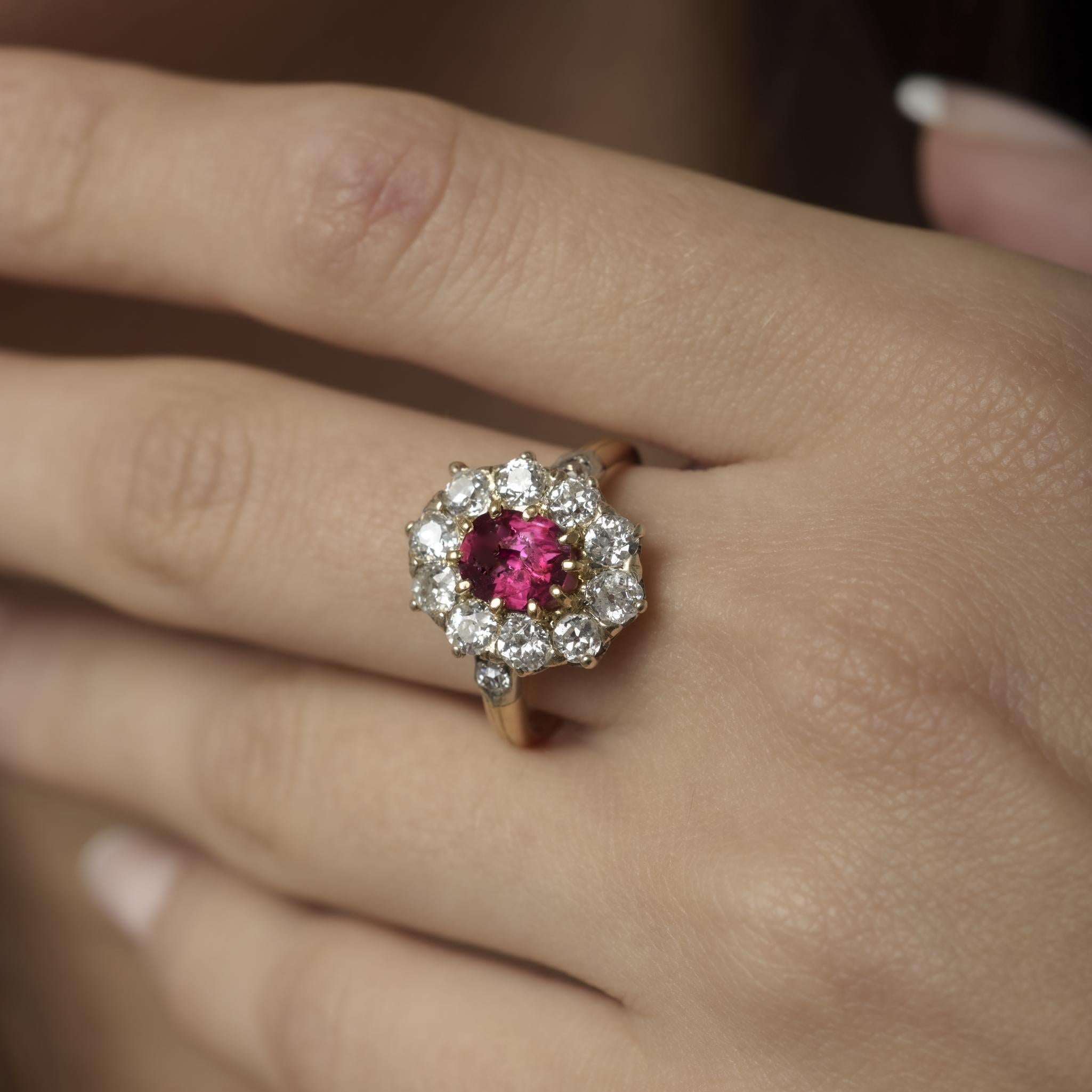 Une élégante bague victorienne mettant en valeur un rubis ovale de 1 carat d'origine thaïlandaise, entouré de 1,90 carat de diamants étincelants de taille ancienne dans un riche or jaune et de l'argent.