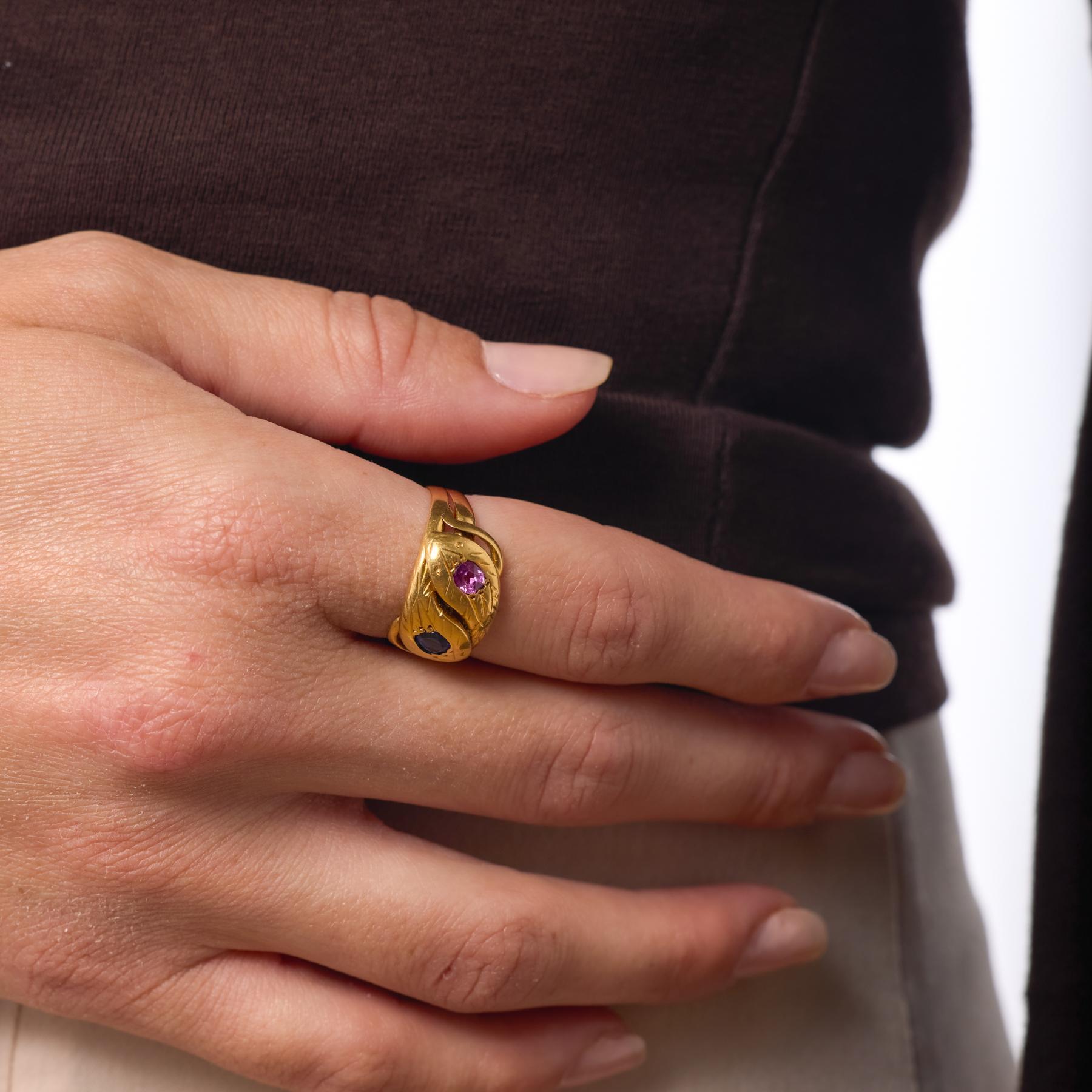 Cette bague serpent victorienne française s'enroule gracieusement autour du doigt, sa forme spiralée étant couronnée de saphirs appariés - l'un rose, l'autre bleu - qui brillent doucement sur l'or jaune riche. La silhouette serpentine capture la