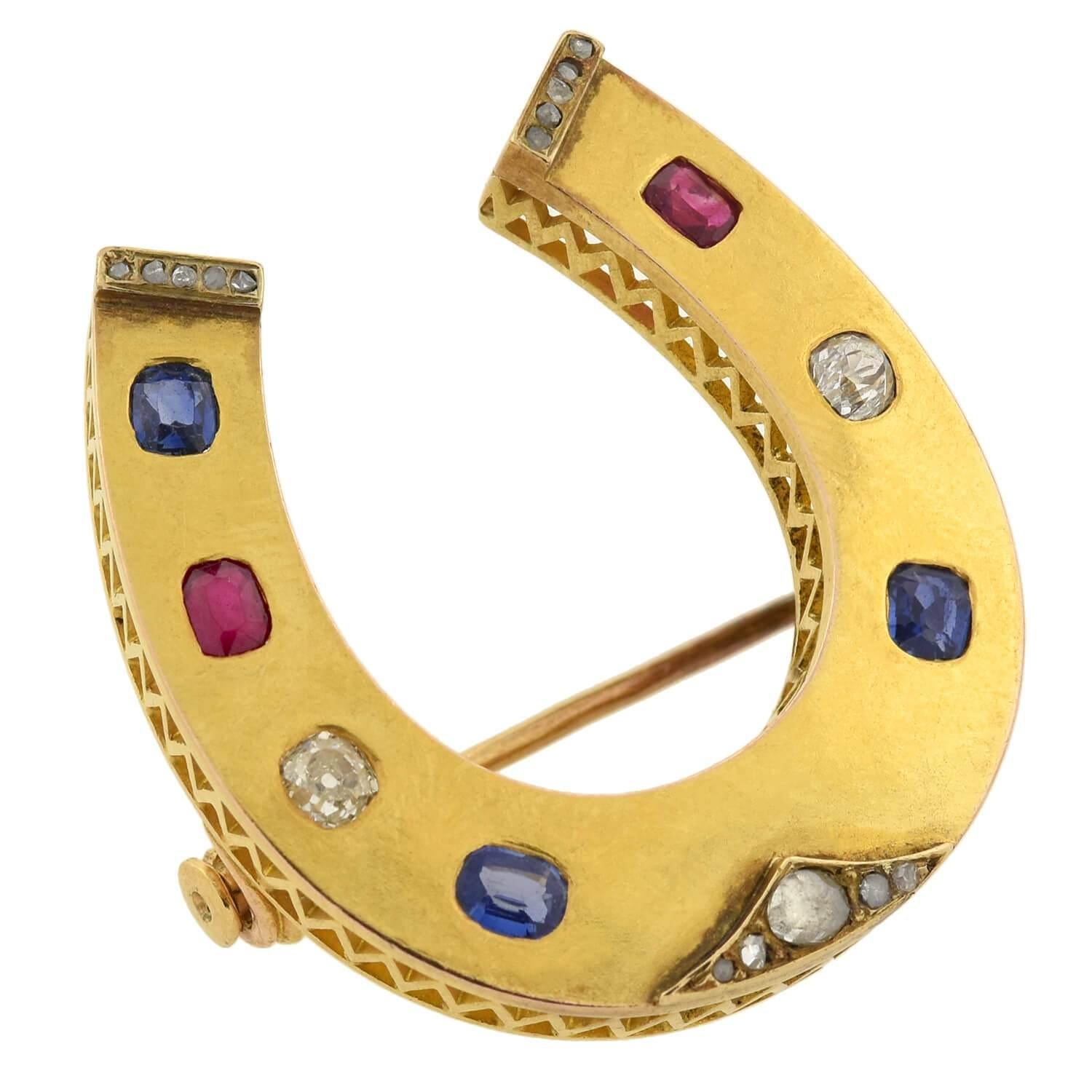 An absolutely exquisite gemstone pin from the Victorian (ca1847-1919) era! Crafted in vibrant 18kt yellow gold, this fantastic piece consists of a relatively large horseshoe motif lined with 7 (always 7 for good luck!) rich gemstones. The smoothly